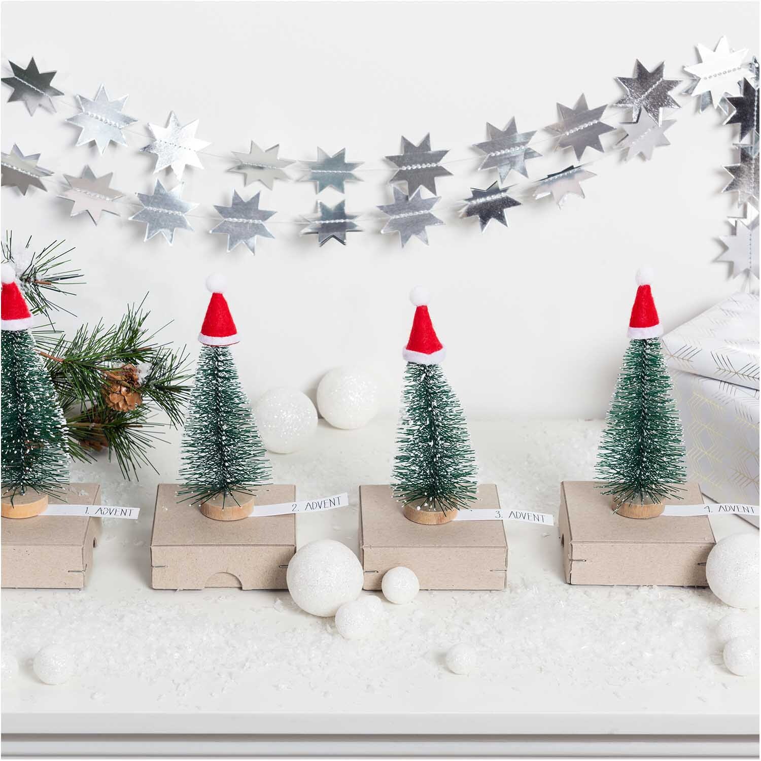 Ritzschachtel quadratisch Größe 10x10x3,5cm von Rico Design Ritzschachtel quadratisch: Vier Mini-Weihnachtsbäume mit roten Mützen auf quadratischen Schachteln, dekoriert mit silbernen Sternen.