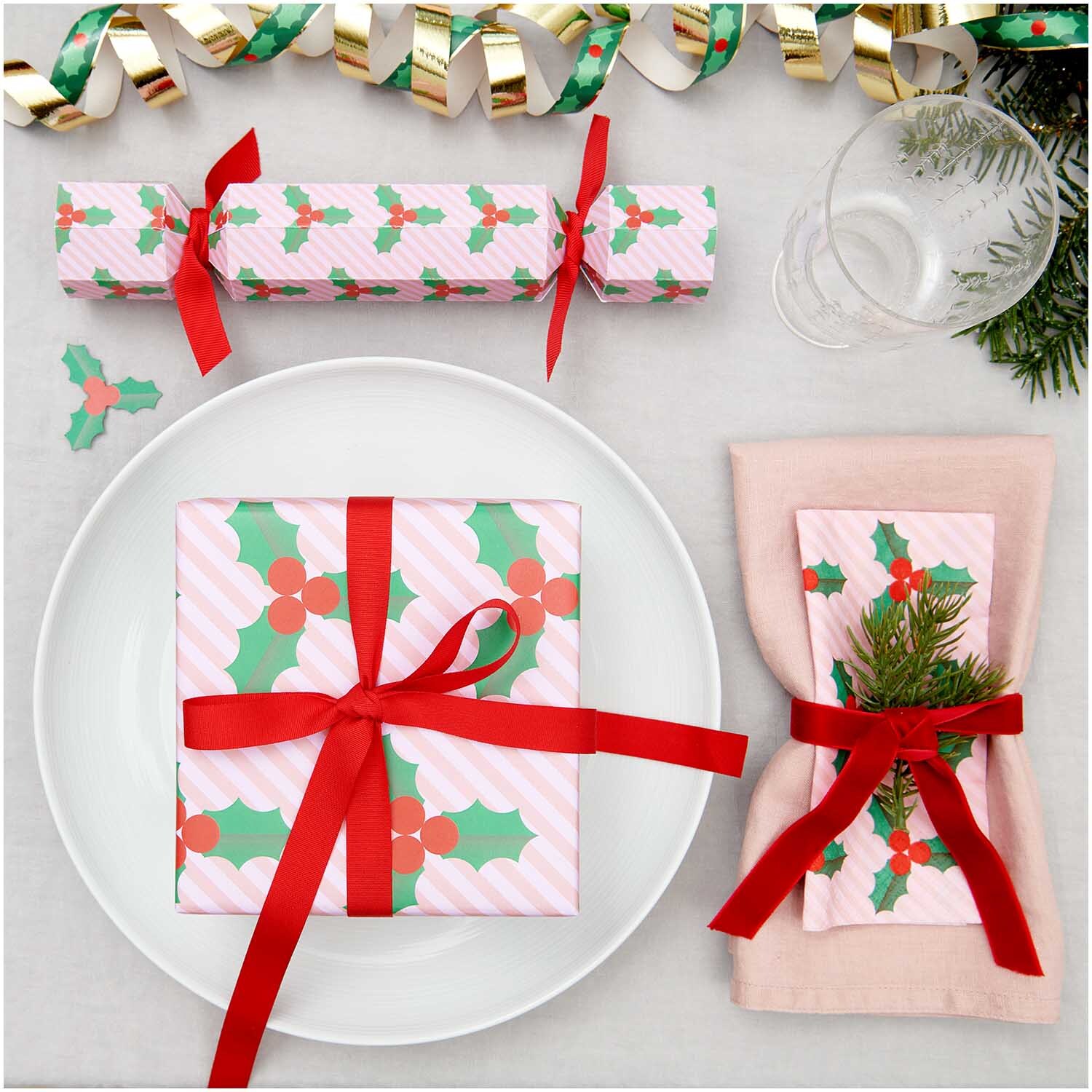 Servietten Ilex 33x33cm 20 Stück von Rico Design Servietten Ilex 33x33cm 20 Stück, dekoriert mit roten Schleifen und Ilex-Muster, auf einem festlichen Tisch mit Geschenk und Besteck.