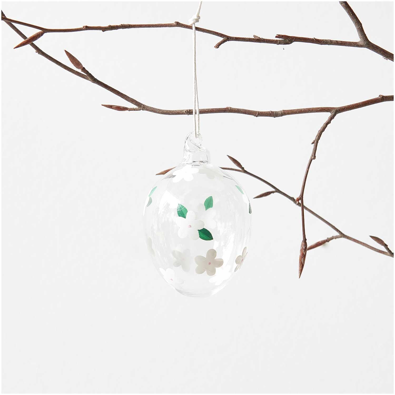 Glas Ei Erdbeerblüte handbemalt Ø 6cm von Rico Design Glas Ei Erdbeerblüte handbemalt Ø 6cm von Rico Design, hängend an einem kahlen Ast, mit floralen Mustern.