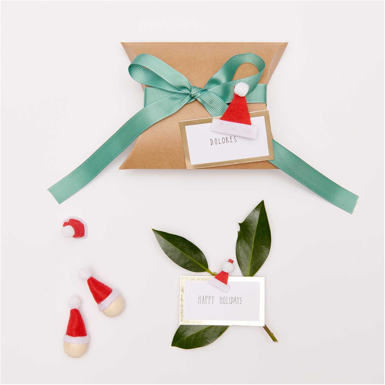 Dekoklammern Weihnachtsmützen rot 3,5cm 6 Stück von Rico Design Dekoklammern Weihnachtsmützen von Rico Design auf Geschenkverpackung mit grünem Band und Grußkarten.