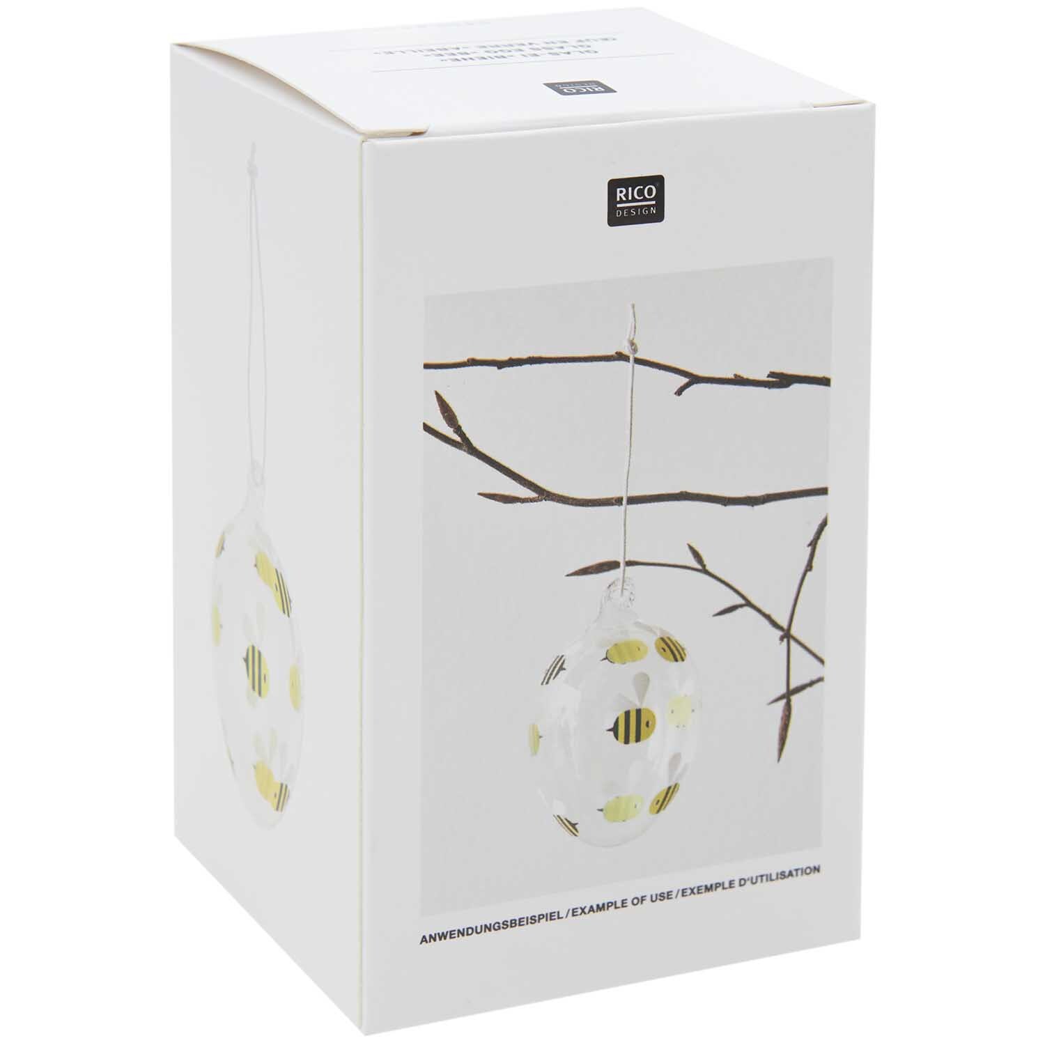 Glas Ei Biene Ø 6cm von Rico Design Glas Ei Biene Ø 6cm von Rico Design, dekoriert mit Bienenmotiv, hängt an einem Ast.