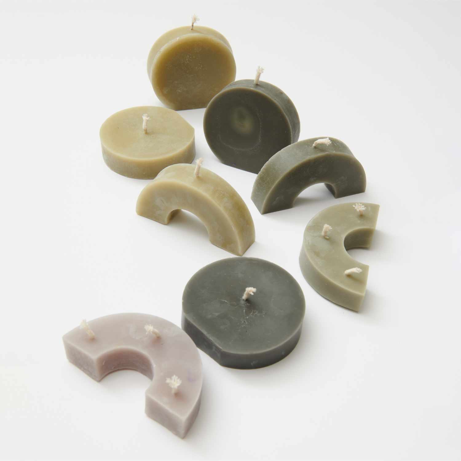 Kerzengießform flach Kreis 100x103x30mm von Rico Design: Verschiedene geformte Kerzen in natürlichen Tönen auf weißem Hintergrund.