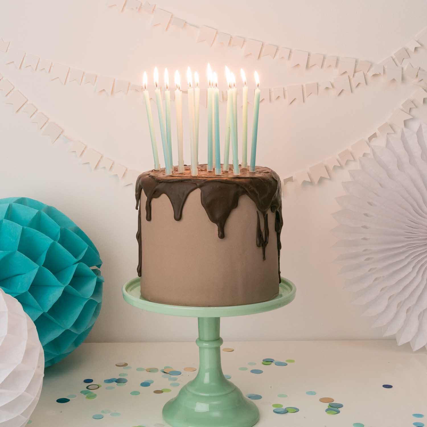 Kerzen lang 16 Stück auf einer Torte mit Schokoladenglasur, dekoriert mit Partydekorationen.