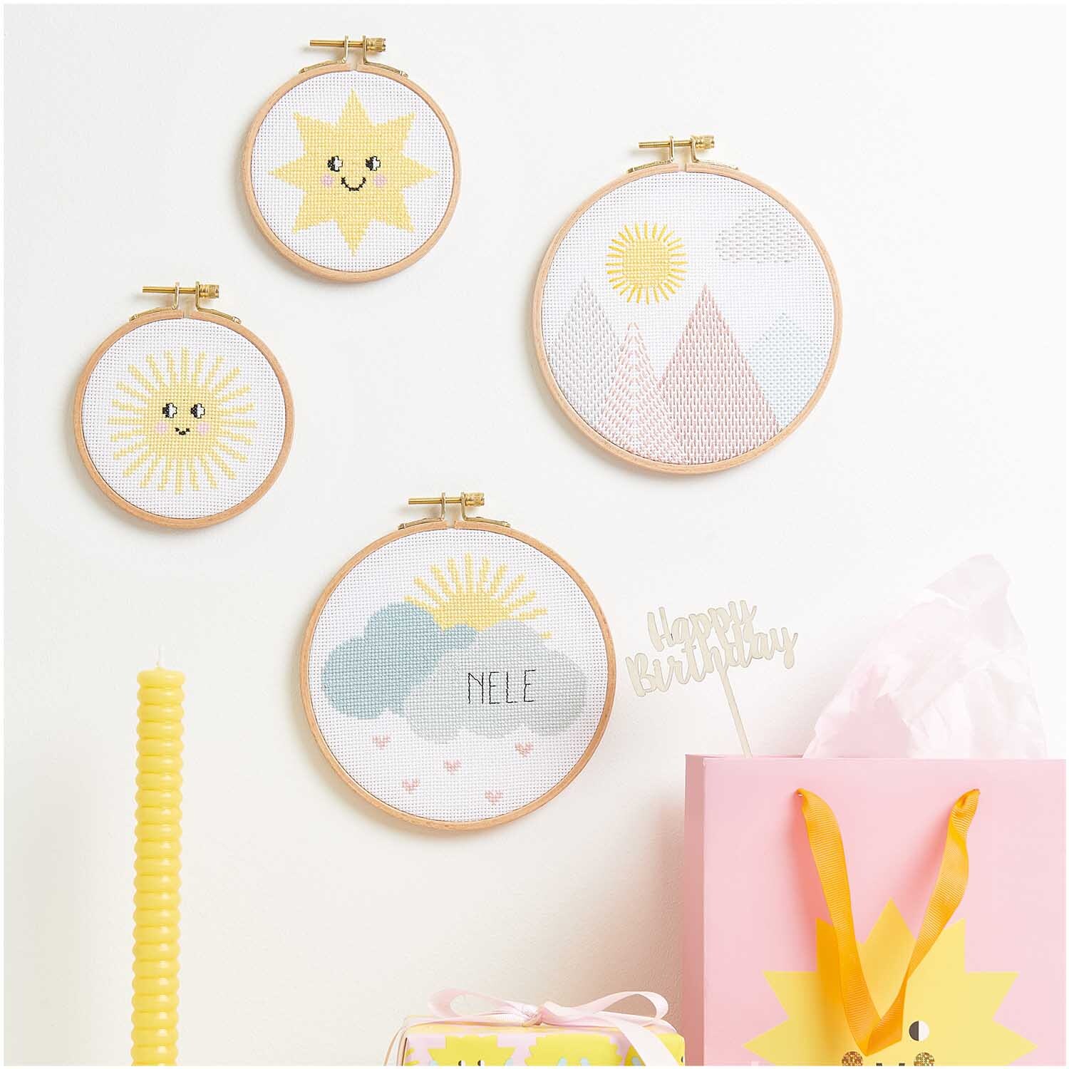 Kit de broderie Happy Sun from Rico Design Stickpackung Happy Sun: Vier Stickrahmen mit Sonnen- und Bergmotiven, dekorativ arrangiert.