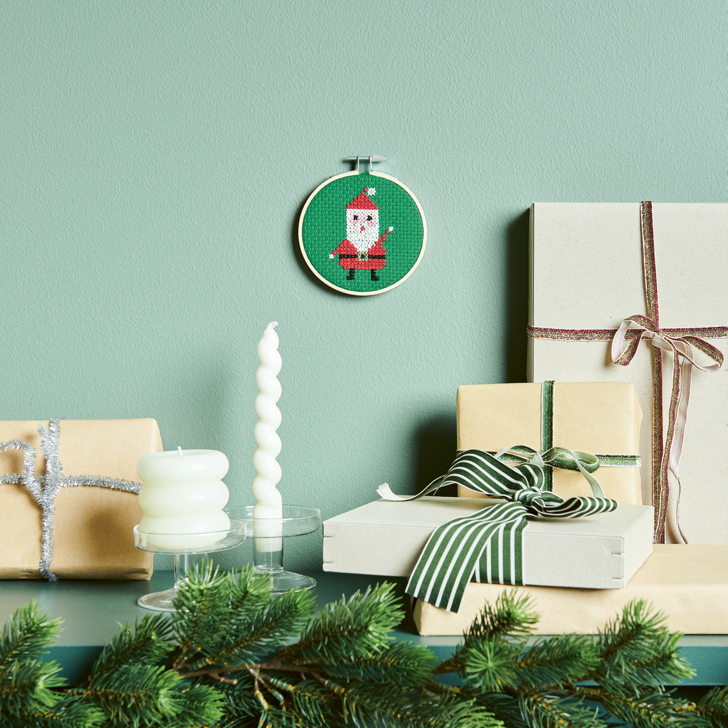 Stickpackung Bild Nikolaus Ø10cm von Rico Design Stickpackung Bild Nikolaus zeigt ein gesticktes Nikolausmotiv in einem Ø10cm Rahmen, dekorativ platziert neben Geschenken und Kerzen.