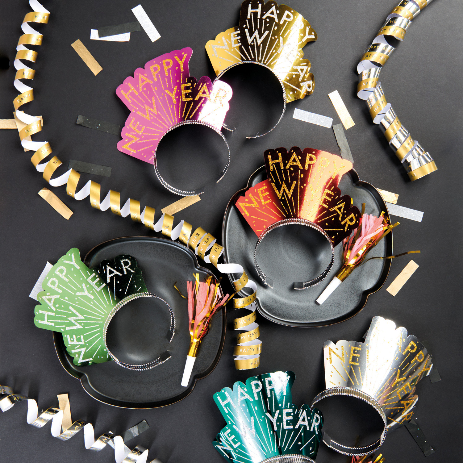 Haarreifen Happy New Year 6 Stück von Rico Design Haarreifen Happy New Year 6 Stück von Rico Design in verschiedenen Farben auf schwarzem Hintergrund, umgeben von goldenen und silbernen Partydekorationen.