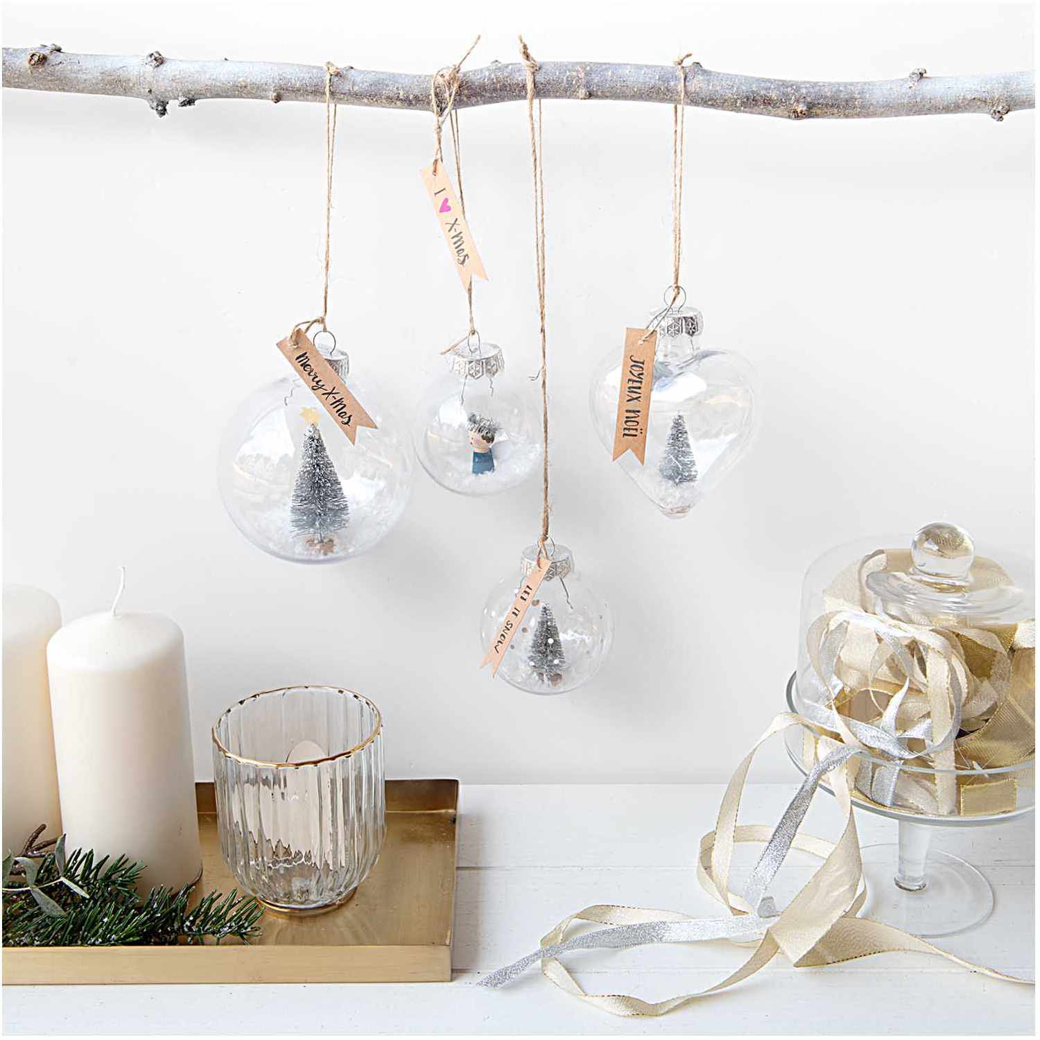 Weihnachtskugel aus Kunststoff 7cm von Rico Design Weihnachtskugel aus Kunststoff 7cm, transparent, von Rico Design, hängt an einem Ast mit weiteren Dekorationen.