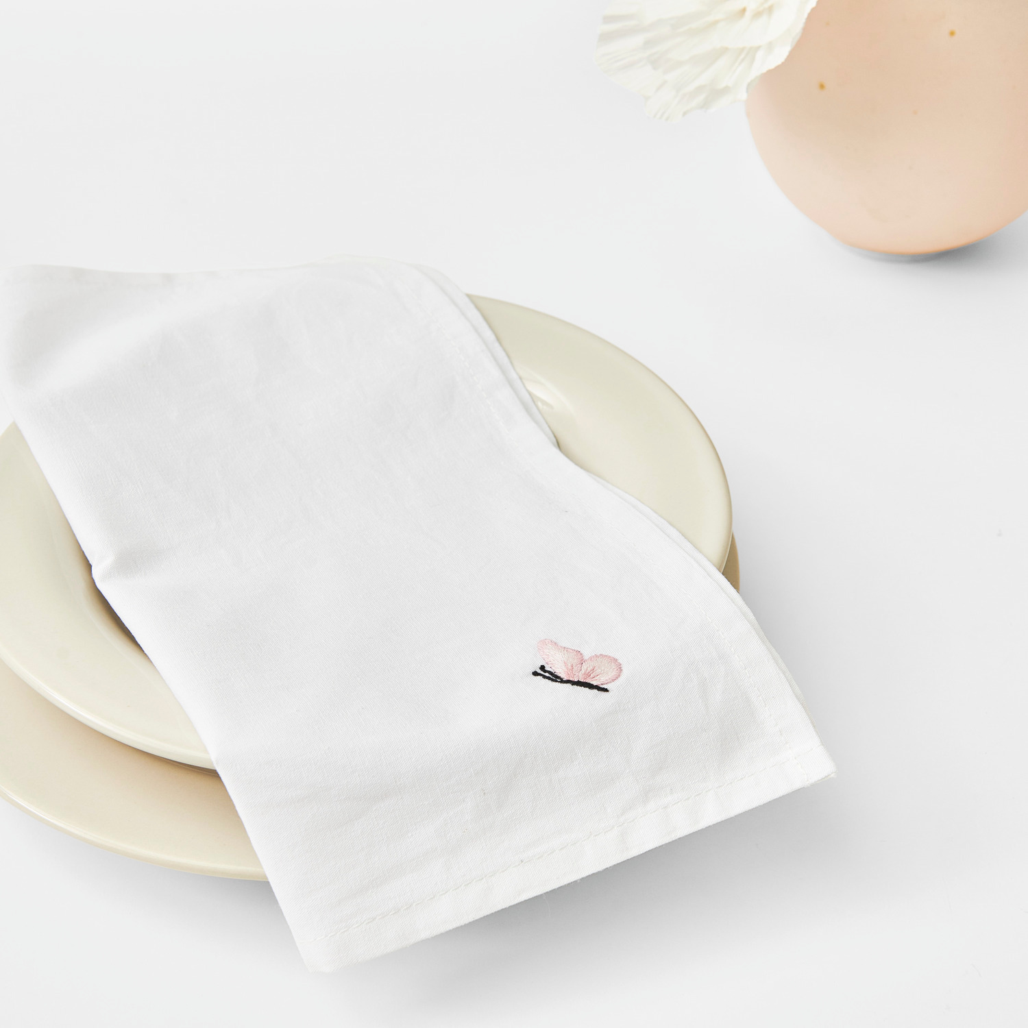 Stoffserviette 2 Stück weiß Größe 30x30cm von Rico Design Stoffserviette 2 Stück weiß von Rico Design auf einem Teller, elegant gefaltet mit zartem Muster.