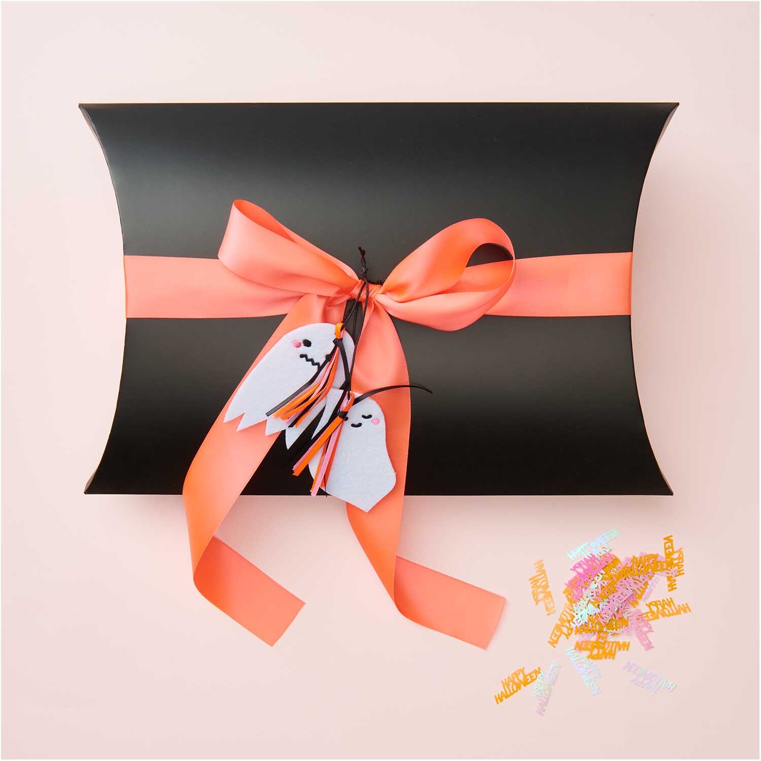 Filzhänger Gespenst freundlich weiß 10x5,6cm von Rico Design Filzhänger Gespenst freundlich weiß von Rico Design an schwarzer Geschenkbox mit orangener Schleife.