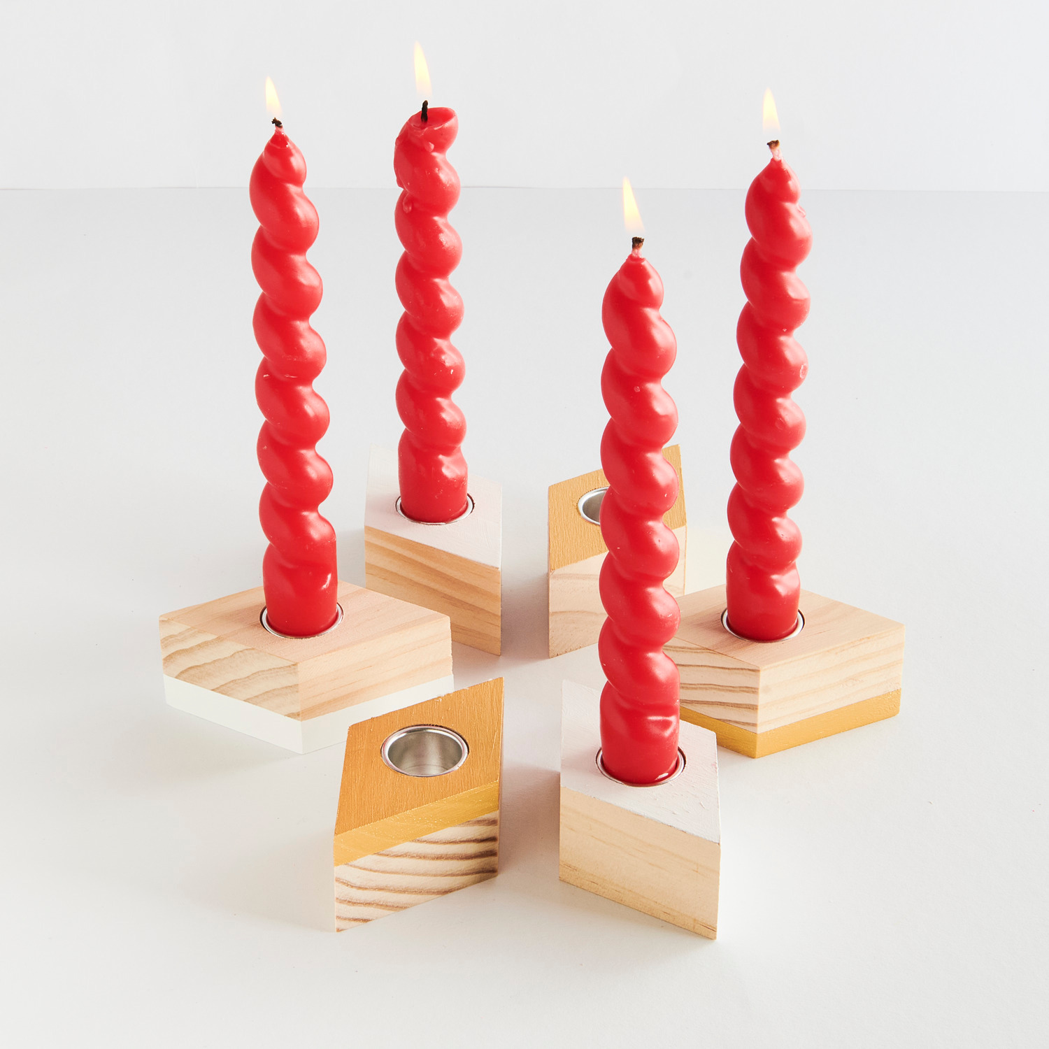 Kerzenhalter Raute für Stabkerzen von Rico Design, aus Holz, präsentiert mit roten Kerzen.