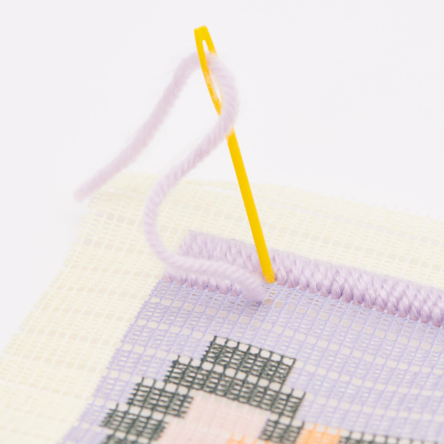 Kit de broderie Longstitch Tigre 18x30cm from Rico Design Longstitch Stickpackung Tiger: Nahaufnahme eines Stickprojekts mit gelber Nadel und lila Garn.