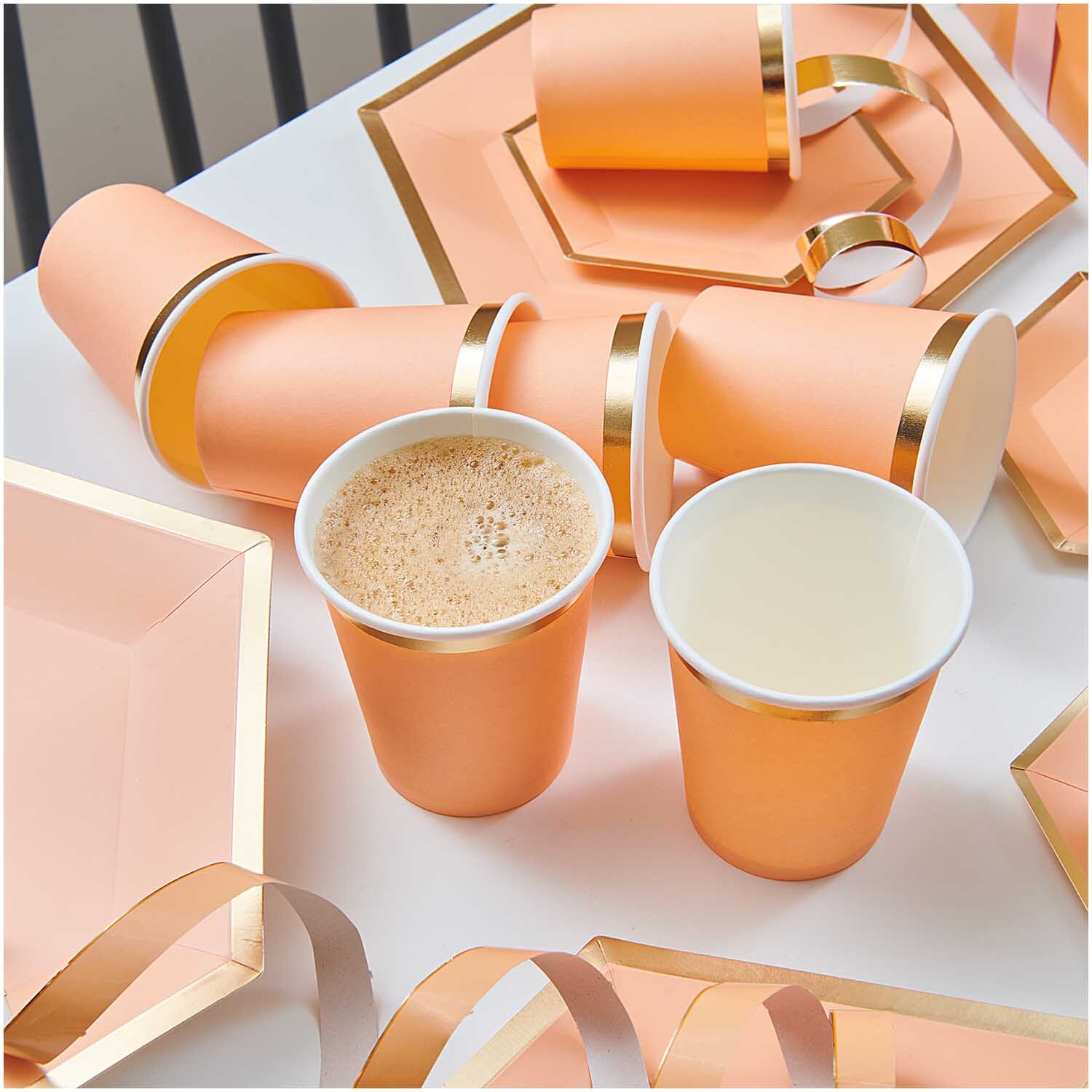 Pappbecher apricot-gold 250ml 10 Stück von Rico Design Pappbecher apricot-gold 250ml 10 Stück von Rico Design auf einem Tisch mit passenden Tellern und Bändern.