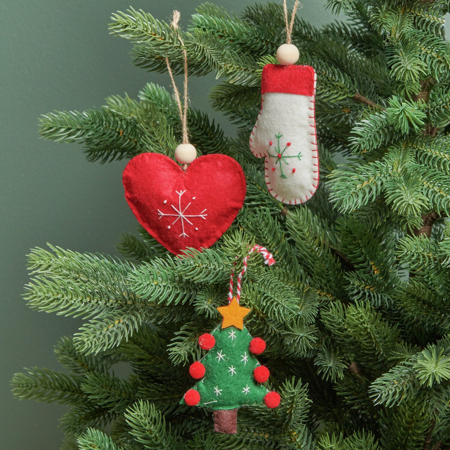 Weihnachtsbaum Filz 9x2x7cm Farbe Grün von Rico Design Filzhandschuh Weiß Rot: Weihnachtsschmuck aus Filz mit Herz, Handschuh und Baum, verziert mit Stickerei, hängt an einem Tannenbaum.