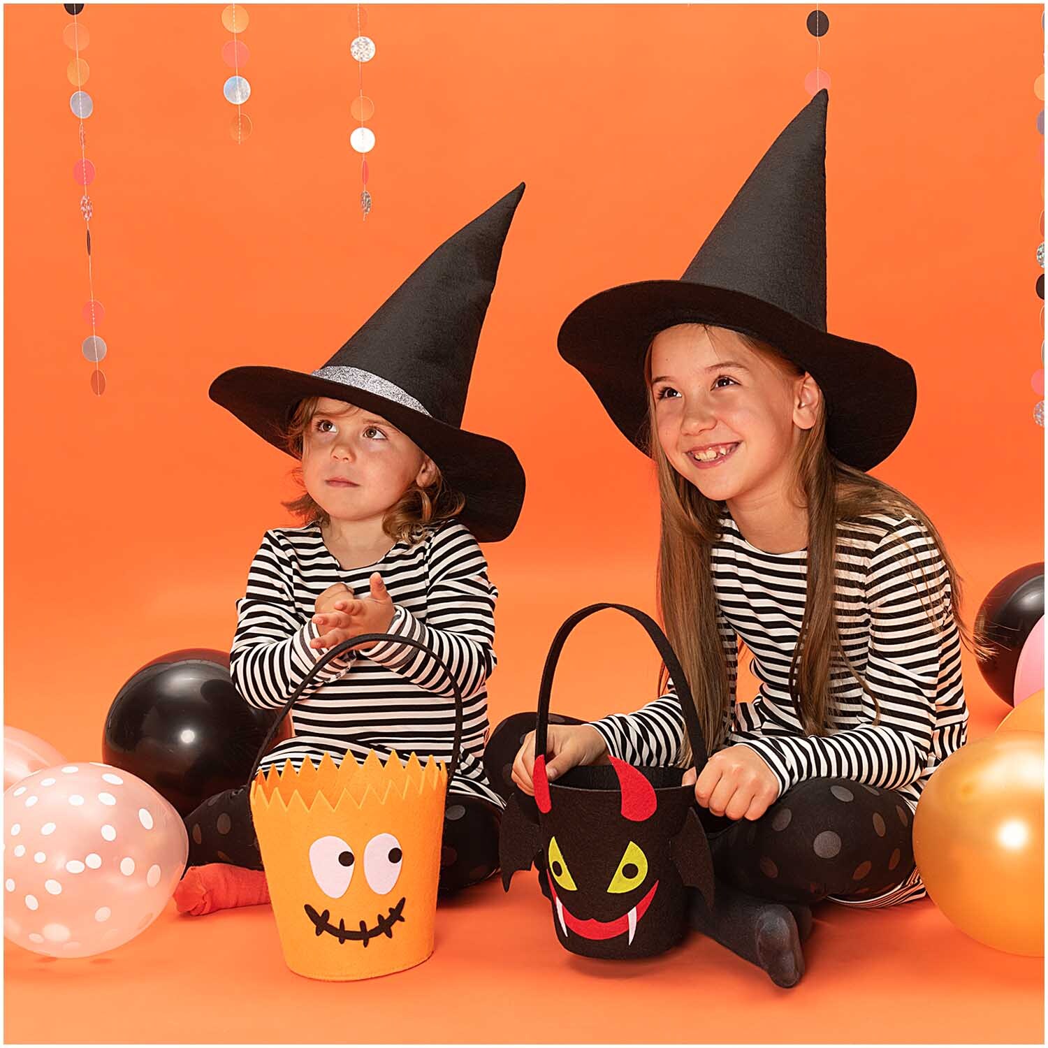 Halloween Filzkorb schwarz 16x16cm von Rico Design Halloween Filzkorb schwarz 16x16cm: Zwei Kinder in Hexenkostümen mit Filzkörben, umgeben von Luftballons.