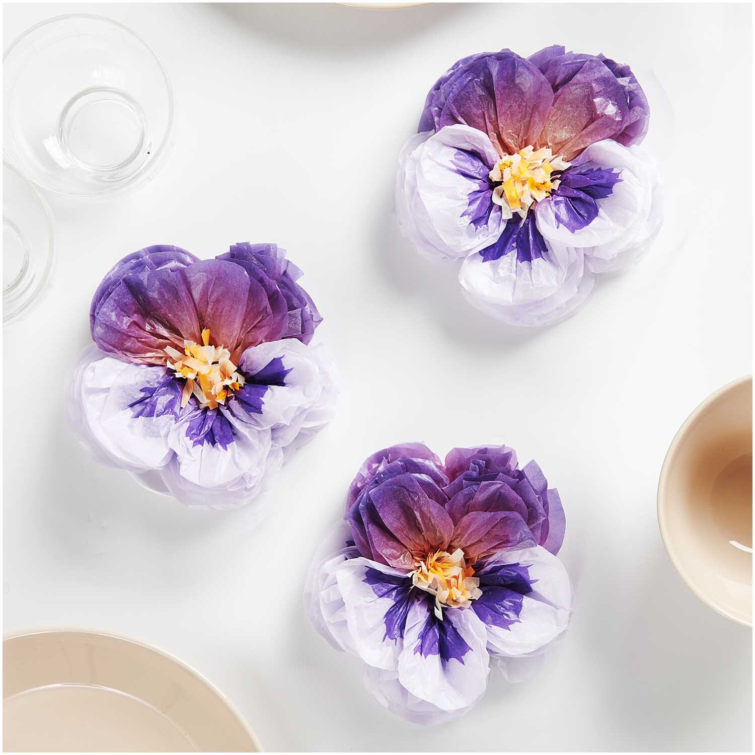 Seidenpapierblumen Stiefmütterchen von Rico Design in Lila, kunstvoll arrangiert auf einem Tisch.