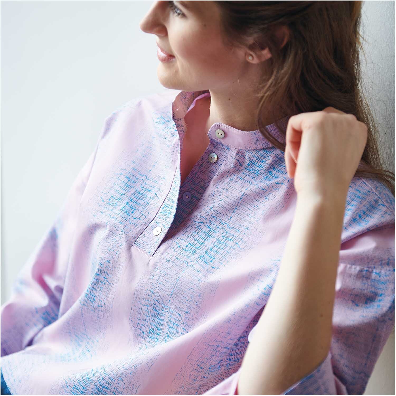 Stoffabschnitt Druckstoff Muster bonbonrosa-azur 50x140cm von Rico Design Stoffabschnitt Druckstoff Muster bonbonrosa-azur von Rico Design, zeigt eine Frau in pastellfarbener Bluse mit dezentem Muster, ideal für kreative Nähprojekte.