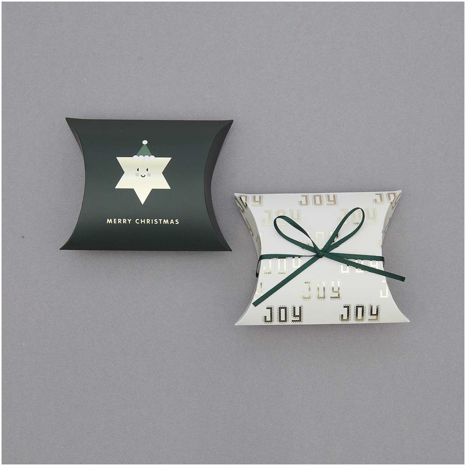 Paper Poetry Satinband 3mm 3m: Zwei Geschenkboxen, eine dunkelgrün mit Sternmotiv und eine weiß mit "JOY"-Aufdruck, verziert mit grünem Satinband.