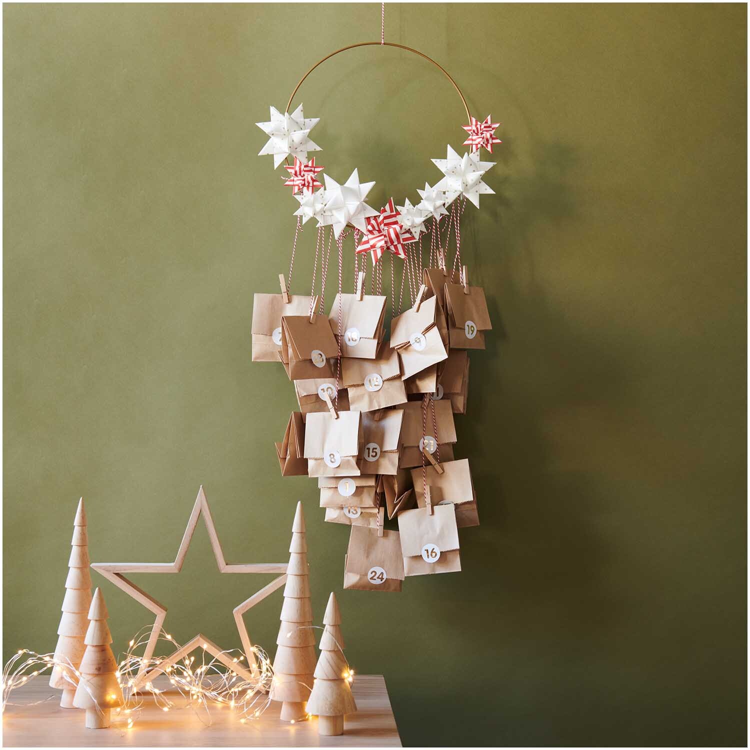 Paper Poetry Adventskalender Sticker Zahlen 1-24: Ein dekorativer Adventskalender mit weißen und roten Sternen, umgeben von kleinen Tannenbäumen.