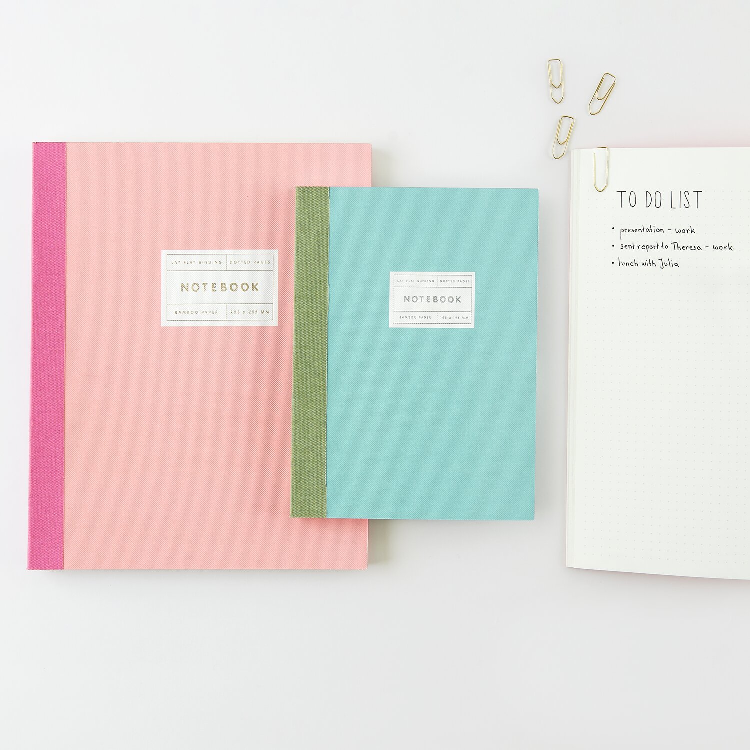 Paper Poetry Notizbuch S Silberrand Farbe Mint von Rico Design Paper Poetry Notizbuch L und S in Koralle und Mint mit Goldrand von Rico Design, auf einem Tisch mit Büroklammern.