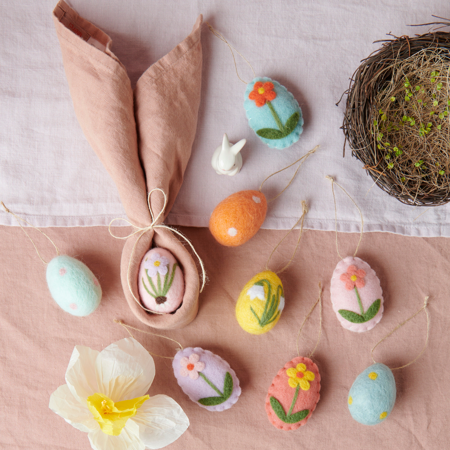 Aufhänger Filz-Eier gepunktet Ø4x6cm 4 Stück von Rico Design Aufhänger Filz-Eier Blumen: Bunte Filz-Eier mit Blumenmotiven, dekorativ arrangiert neben einem Naturnest auf einem Tisch.
