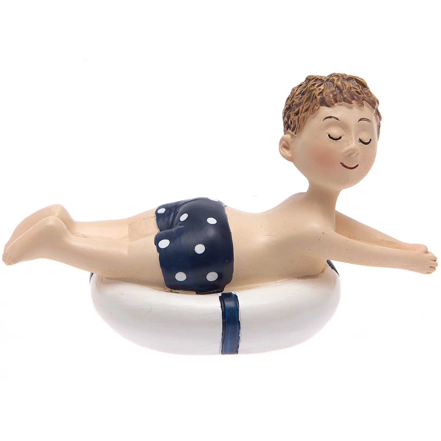 Deko-Figur Junge mit Schwimmreifen von Rico Design, lächelnd, in blauer Badehose mit Punkten.