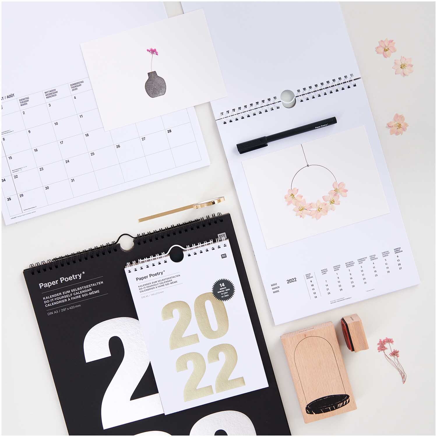 Gepresste Blüten Rittersporn rosa 8 Stück von Rico Design Gepresste Blüten Rittersporn rosa 8 Stück von Rico Design auf einem Schreibtisch mit Kalendern und Stempel.