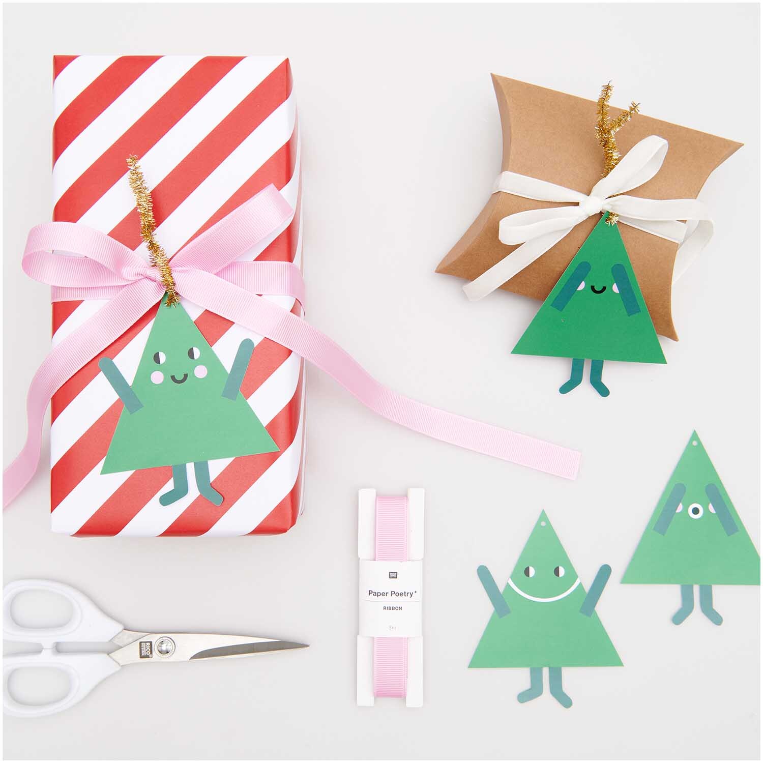 Paper Poetry Geschenkanhänger Tannen 8 Stück von Rico Design Paper Poetry Geschenkanhänger Tannen, 8 Stück, von Rico Design. Zwei Geschenke mit grünen Tannenbaum-Anhängern, rosa Schleifen und Schere.