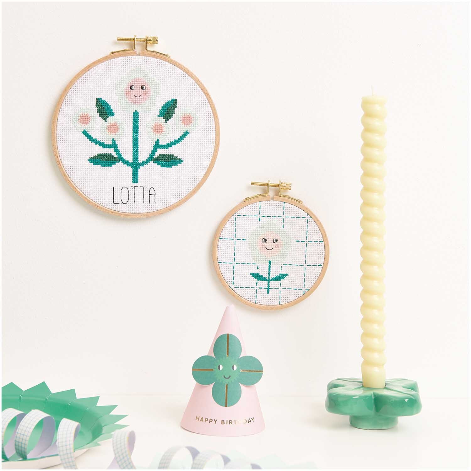 Kit de broderie Happy Flower from Rico Design Stickpackung Happy Flower von Rico Design zeigt zwei bestickte Blumenrahmen mit Kerze und Dekoration.
