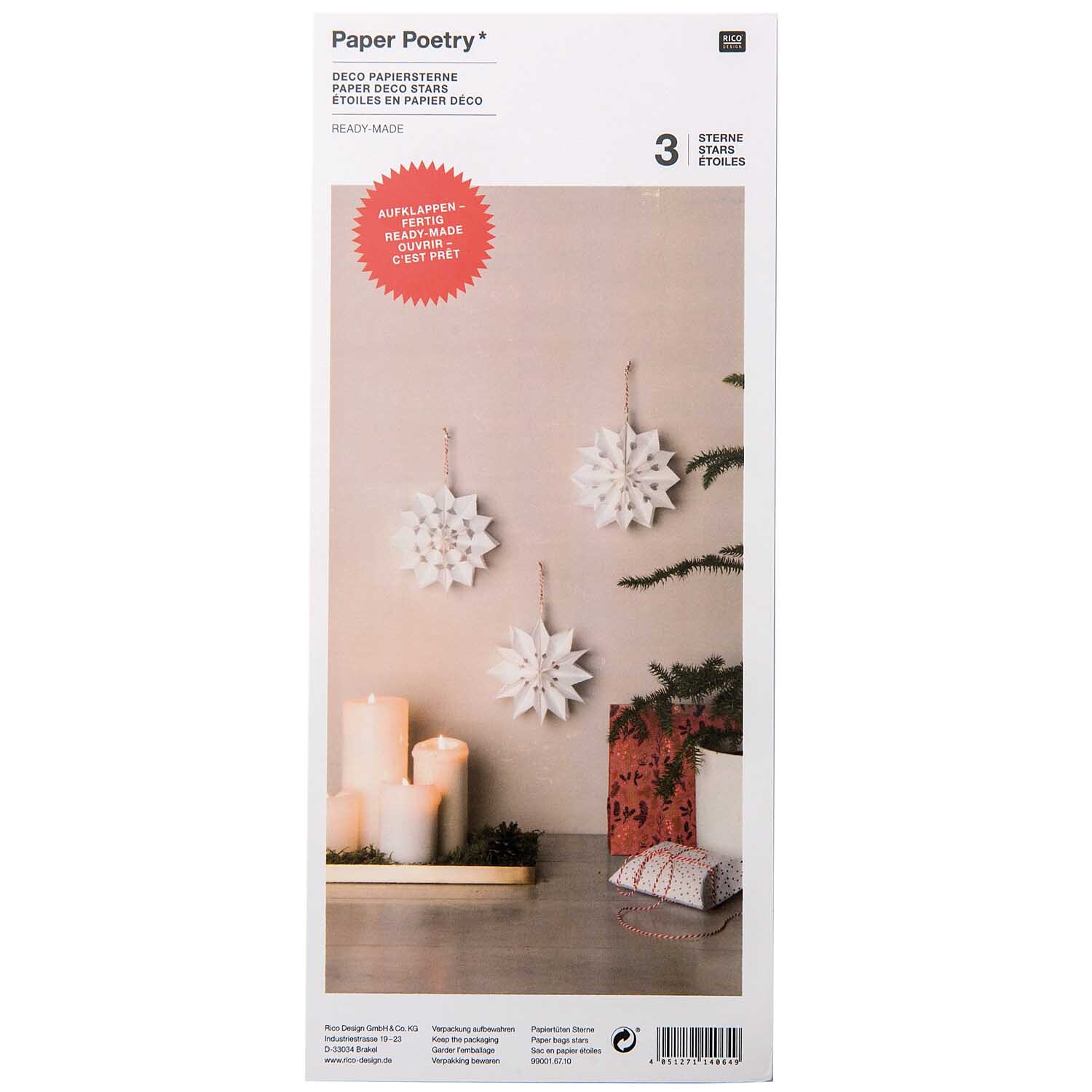 Papiertüten-Sterne weiß klein 3 Sterne von Rico Design, dekorativ an der Wand hängend, neben Kerzen und Geschenken.