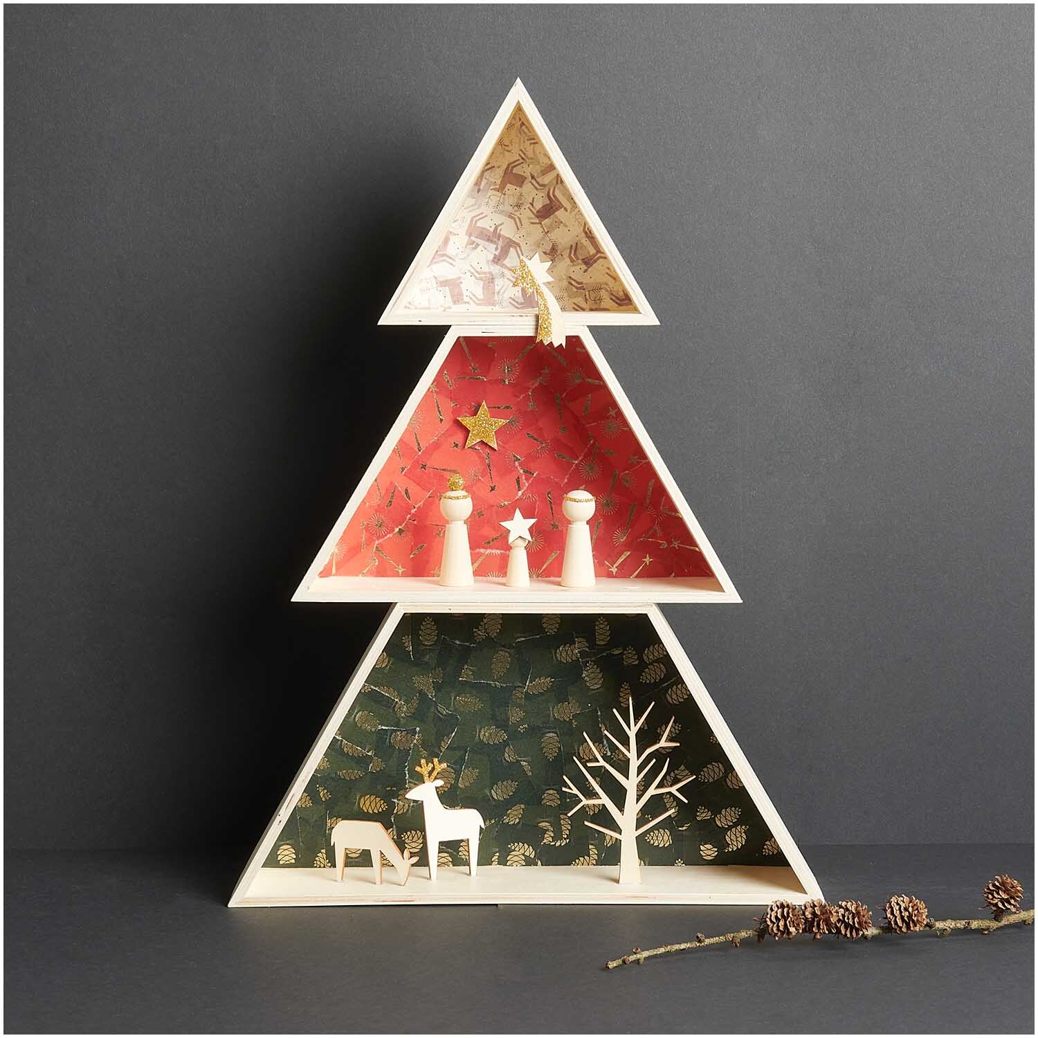 Paper Poetry Paper Patch Papier Sternschnuppen 30x42cm zeigt ein dreieckiges Regal mit weihnachtlichen Figuren und Dekorationen.