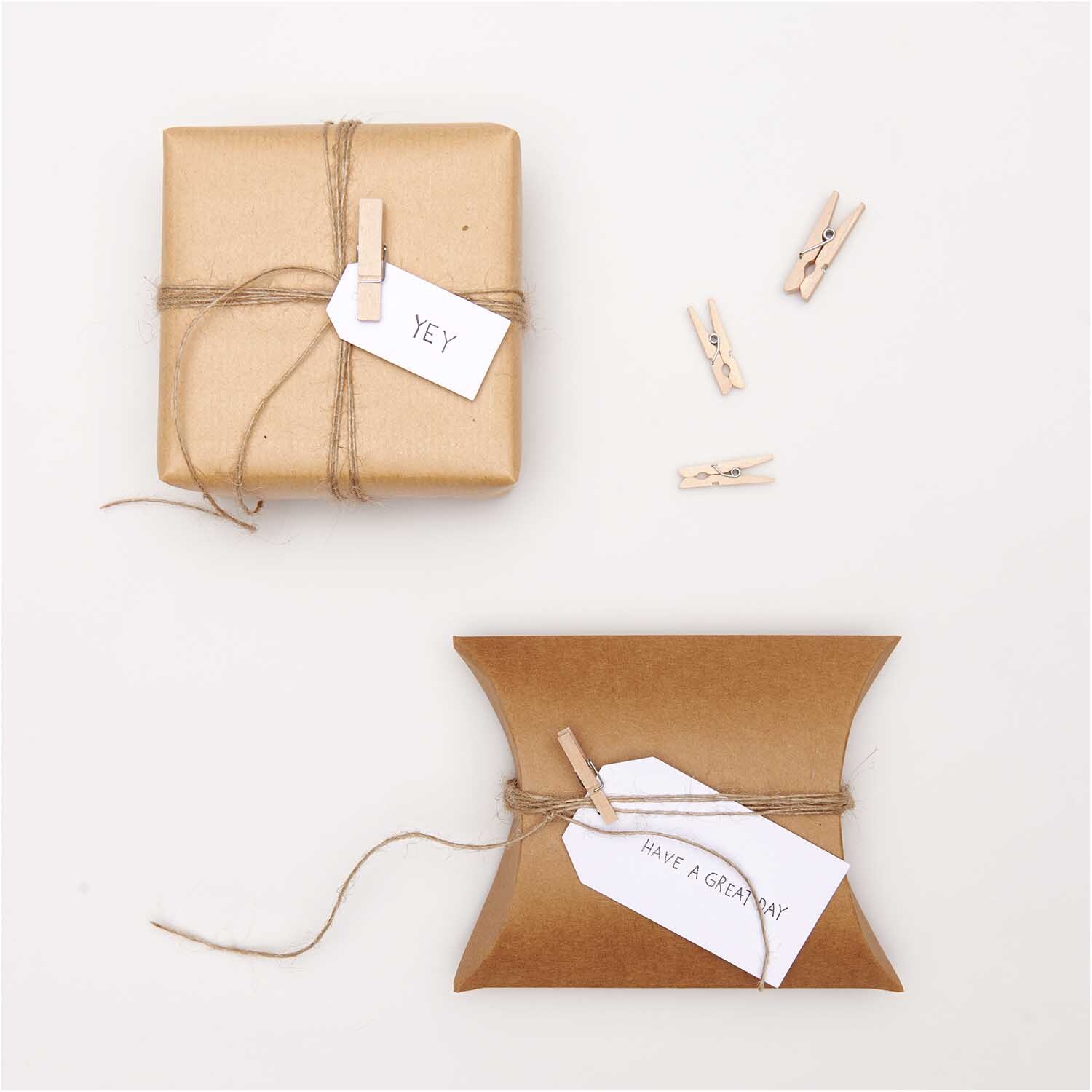 Holzklammern natur 3cm 24 Stück von Rico Design Holzklammern natur 3cm 24 Stück von Rico Design neben zwei verpackten Geschenken mit Etiketten.
