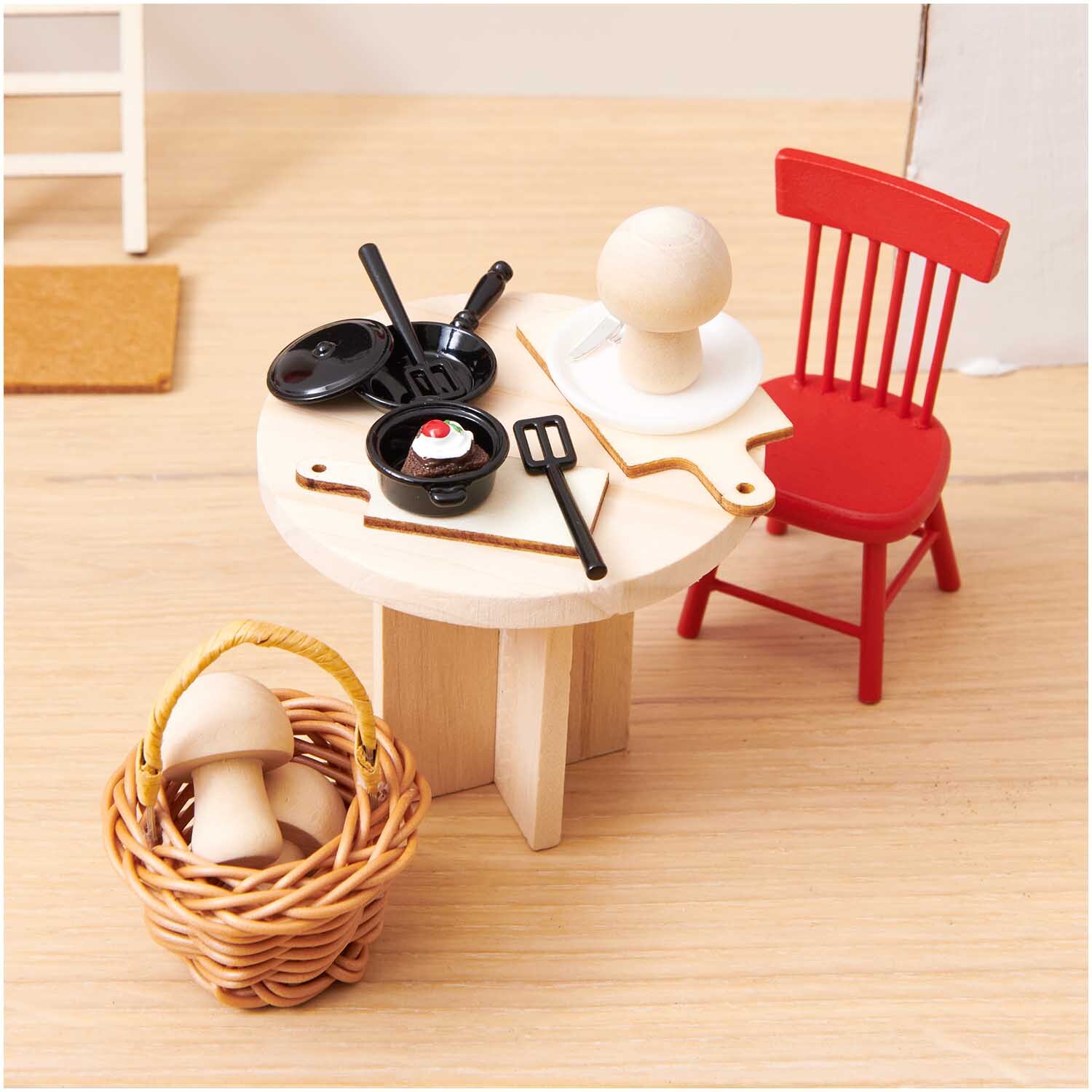 Miniatur Korb mit Henkel 4,5x4,5x6cm Farbe Dunkel von Rico Design Miniatur Korb mit Henkel neben einem Tisch mit Küchenutensilien und einem roten Stuhl.