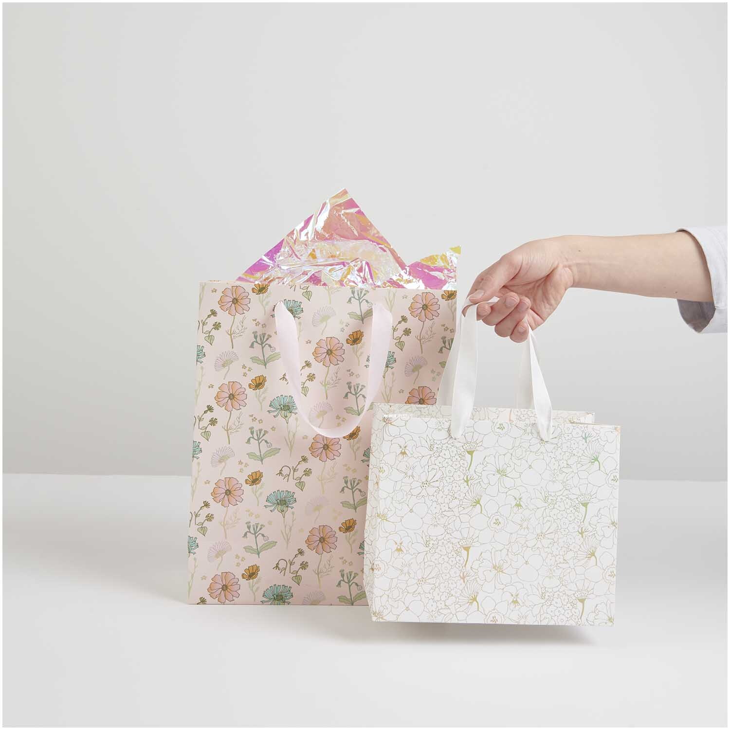 Geschenktüte Blumen Rosa: Zwei dekorative Tüten mit floralen Mustern, eine in Rosa, eine in Weiß.
