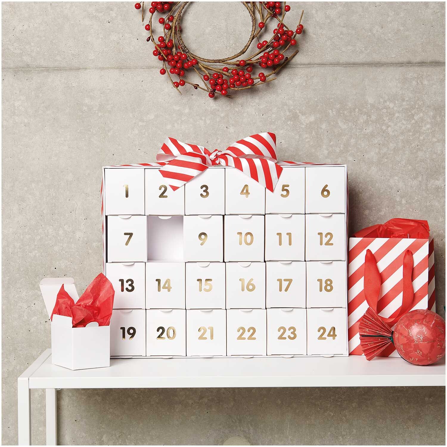 Adventskalender zum Befüllen 36,5x29x6cm Farbe Weiß-Gold von Rico Design Adventskalender zum Befüllen in Weiß-Gold von Rico Design, dekoriert mit roten Akzenten und Schleife.