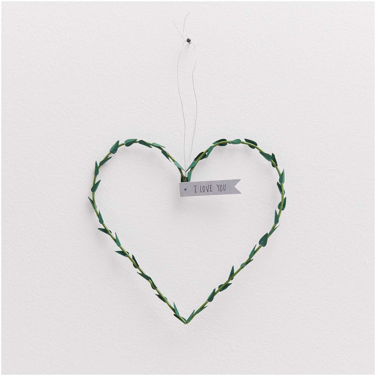 Papierdraht 1,8mm 1m 10 Stück Farbe Grün von Rico Design Papierdraht 1,8mm 1m 10 Stück: Herzförmiger grüner Draht mit "I Love You"-Schild, hängend an weißer Wand.