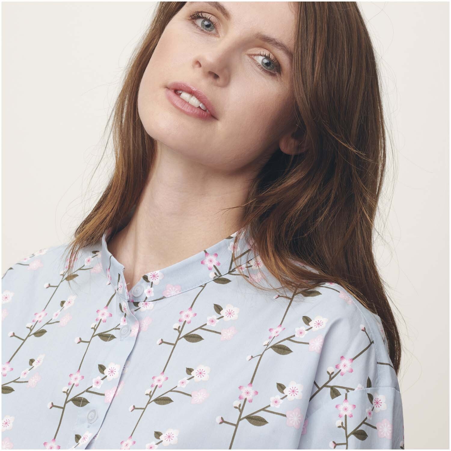 Meterware Baumwoll-Popelin rauchblau Sakura Zweige von Rico Design Meterware Baumwoll-Popelin mit Sakura-Zweigen auf rauchblauem Hintergrund, getragen von einer Frau. Ideal für stilvolle Nähprojekte.