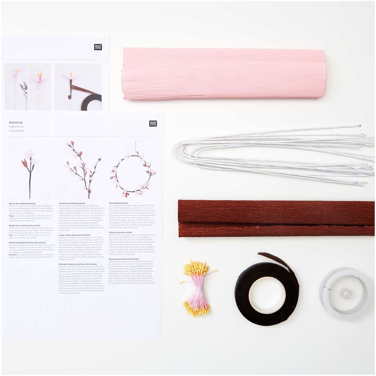 Bastelset Kirschblütenzweig von Rico Design mit rosa Papier, Drähten und Anleitungen auf weißem Hintergrund. Ideal für kreative Projekte.