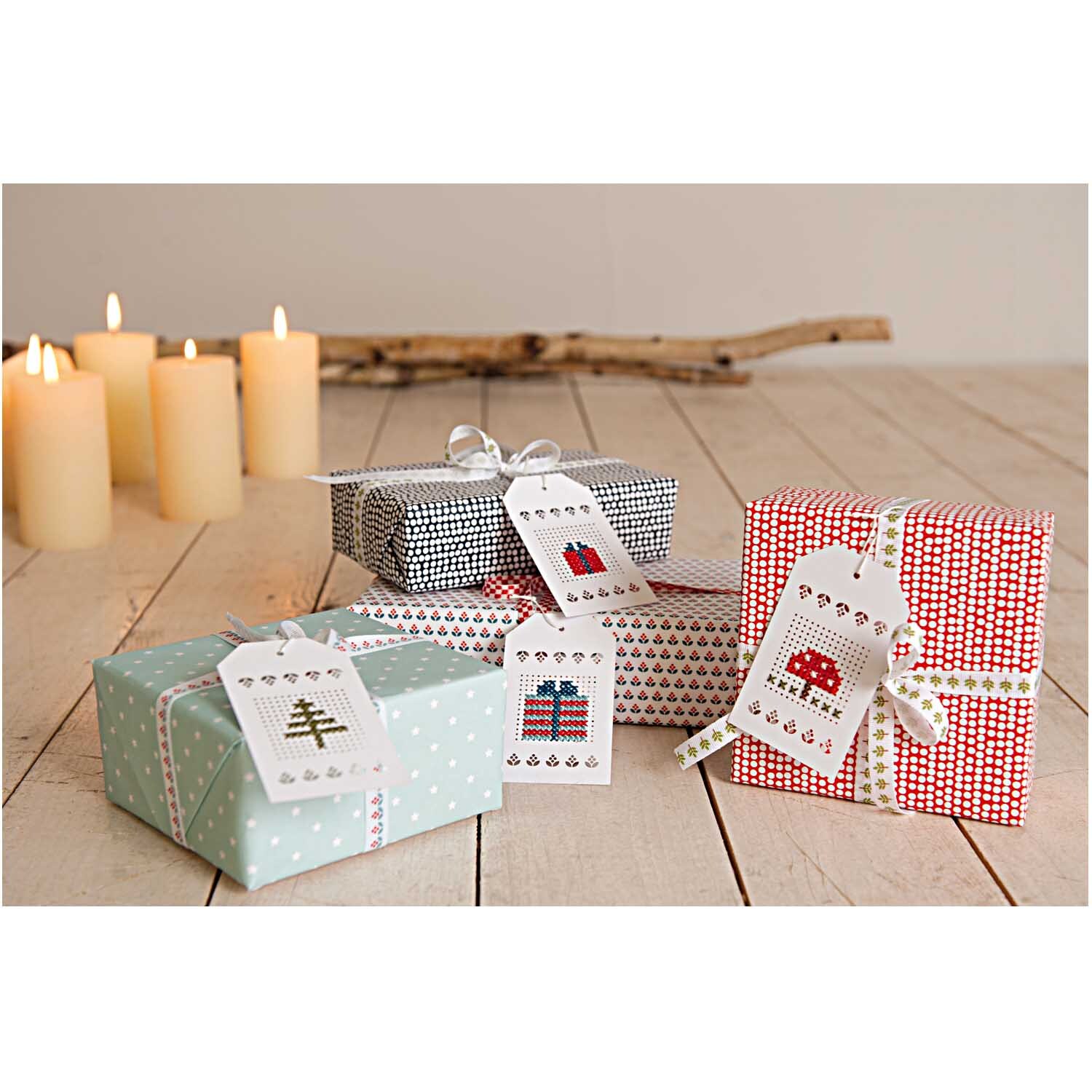 Anhänger zum Besticken creme 24 Stück von Rico Design Anhänger zum Besticken in creme von Rico Design, dekoriert auf Geschenken neben brennenden Kerzen.