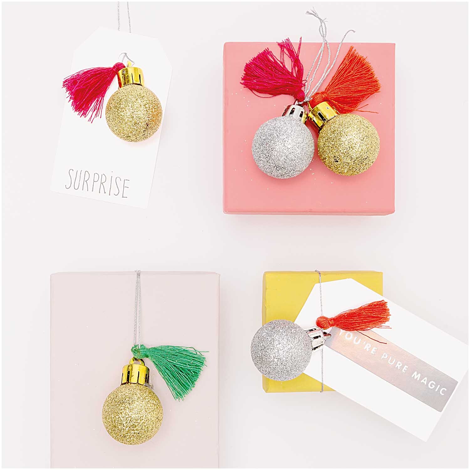 Mini-Kugel-Anhänger rot-grün 6 Stück, dekorativ auf Geschenkboxen arrangiert, mehrfarbig.