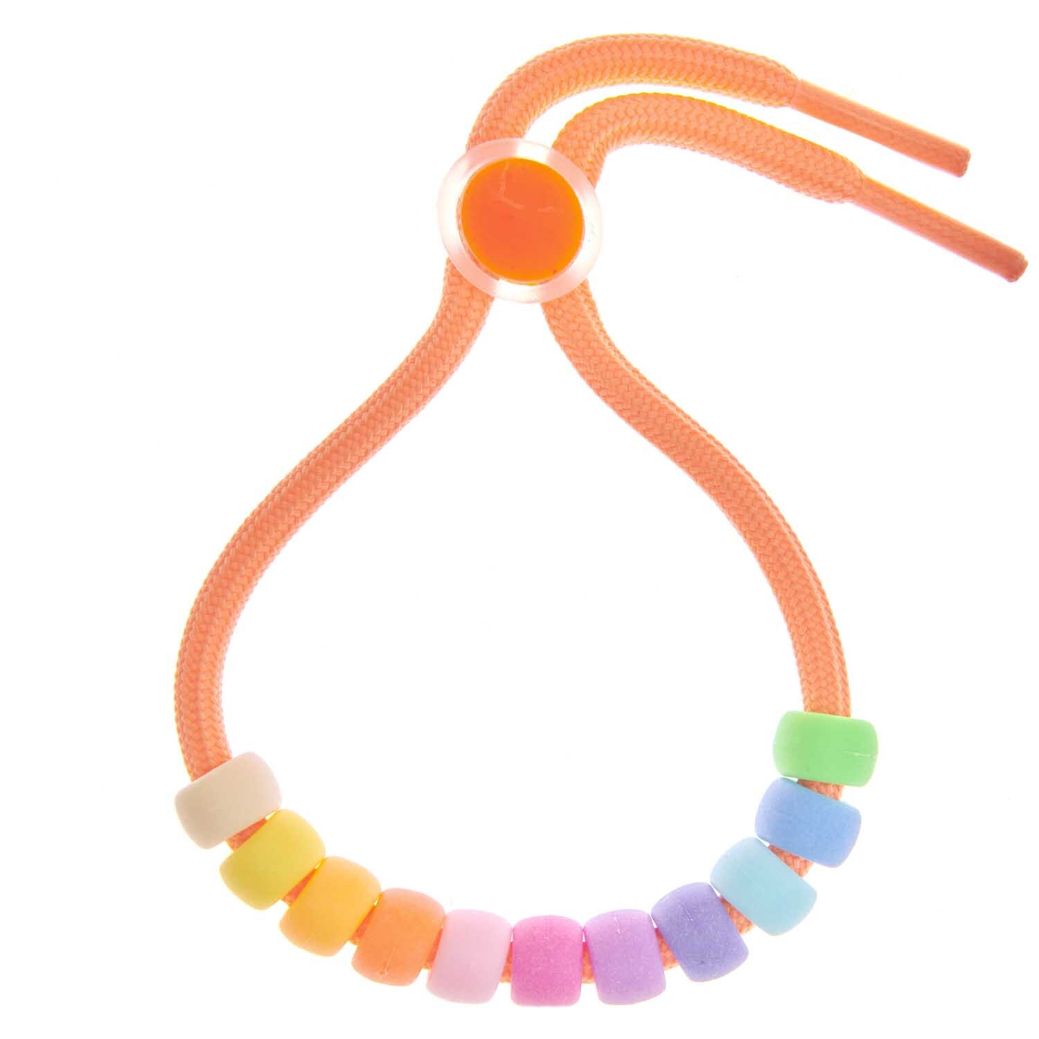 itoshii - Ponii Beads matt Regenbogen 9x6mm 400 Stück von Rico Design Itoshii - Ponii Beads in mattem Regenbogen-Design auf einem orangefarbenen Band von Rico Design.