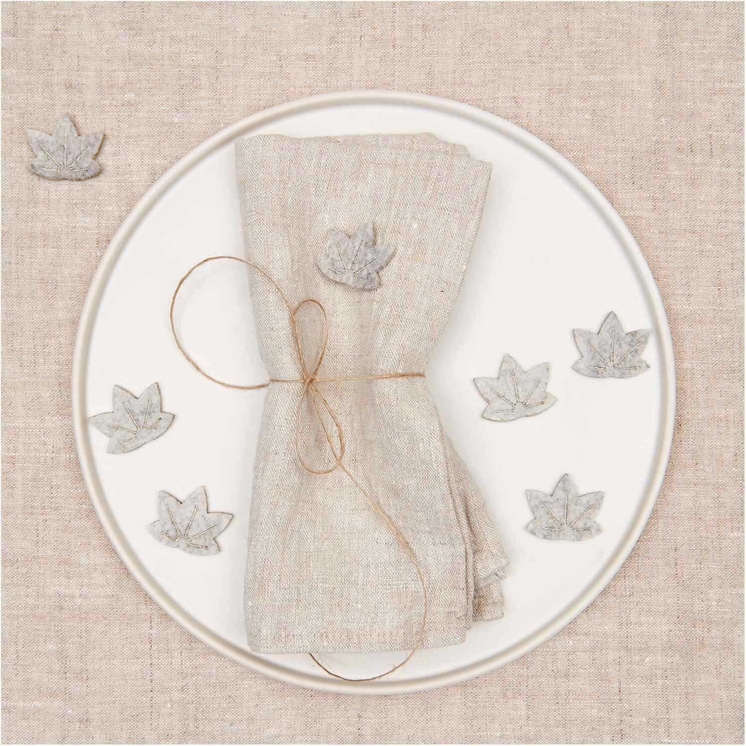 Filzstreu Ahornblatt grau-gold 12 Stück von Rico Design Filzstreu Ahornblatt grau-gold 12 Stück dekoriert einen Teller mit Serviette, ideal für Herbstdeko.