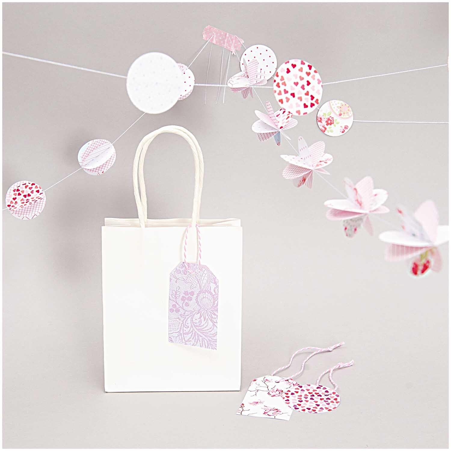 Paper Poetry Motivpapier Block Floral 21x30cm 30 Blatt von Rico Design Paper Poetry Motivpapier Block Floral zeigt eine weiße Geschenktüte mit bunten Papierdekorationen.
