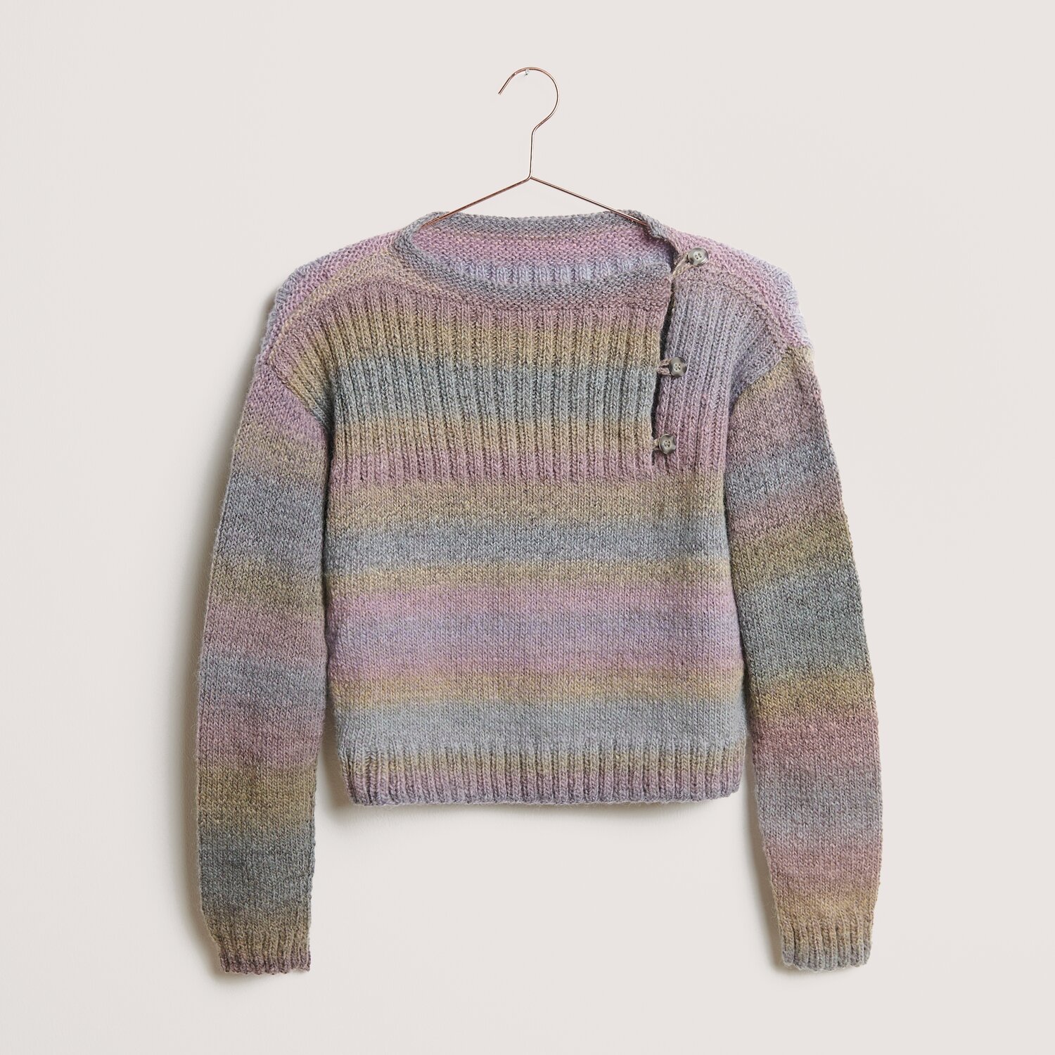 Creative Alpaca Melange Wonderball dk 100g 300m Couleur Pastels from Rico Design Creative Melange Alpaca Wonderball dk Pullover in Pastelltönen, gestrickt mit Rico Design Wolle, zeigt dezente Streifen und Knopfdetails auf der Schulter.
