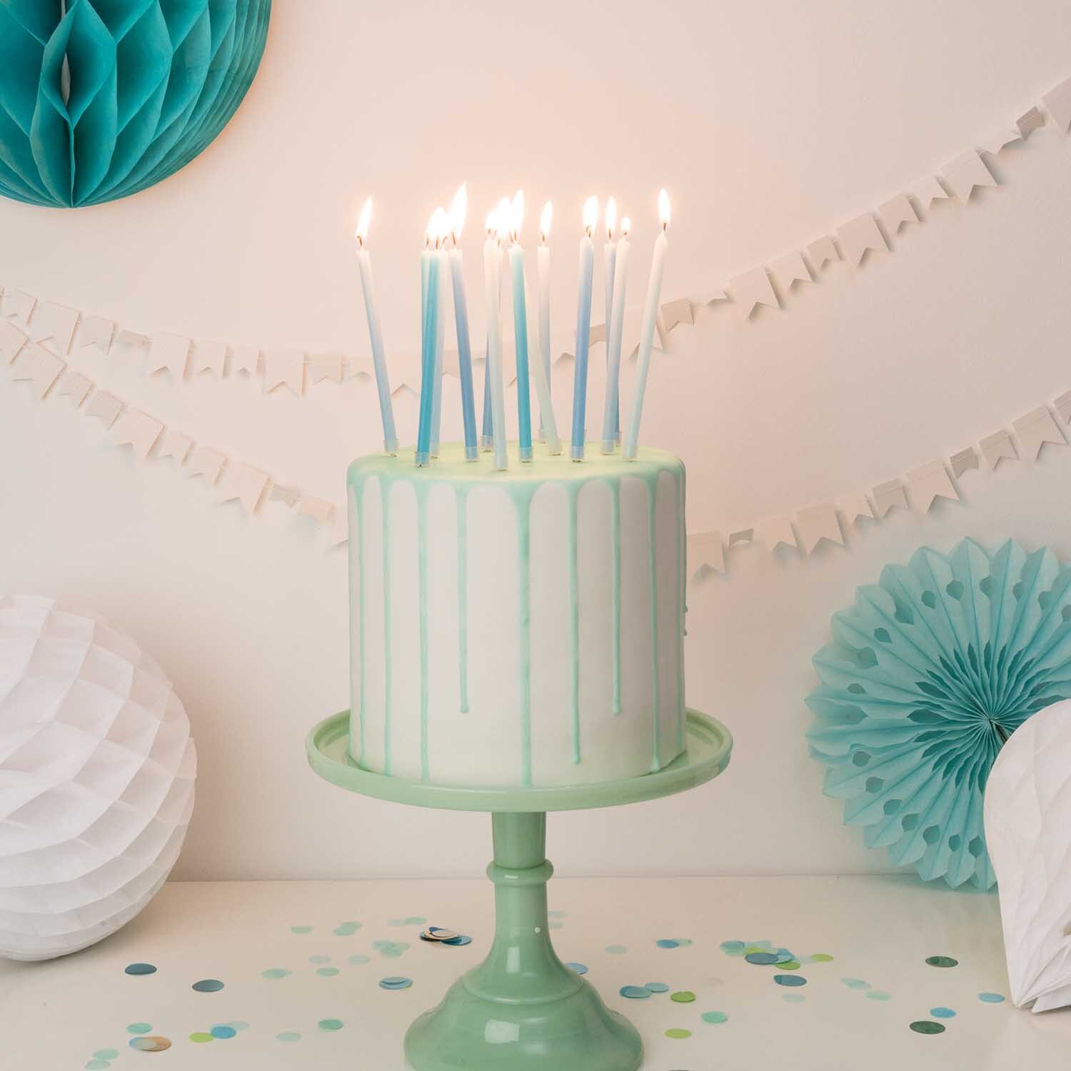 Kerzen lang 16 Stück auf einem dekorierten Kuchen mit aqua-farbenem Ständer und Partydekoration.