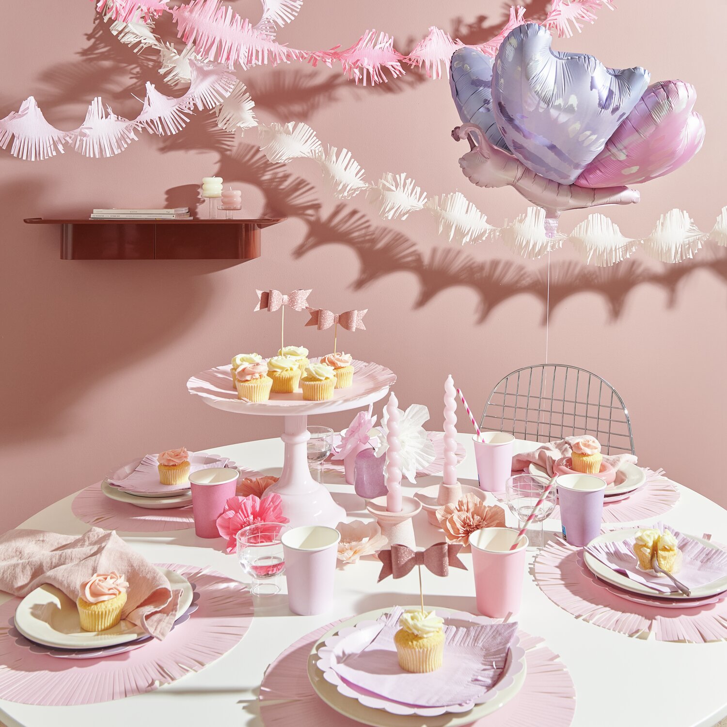 Pappteller Mix Rosa Ø23cm 8 Stück von Rico Design Pappteller Mix Rosa auf einem dekorierten Tisch mit Fransen, Servietten und Partyzubehör.