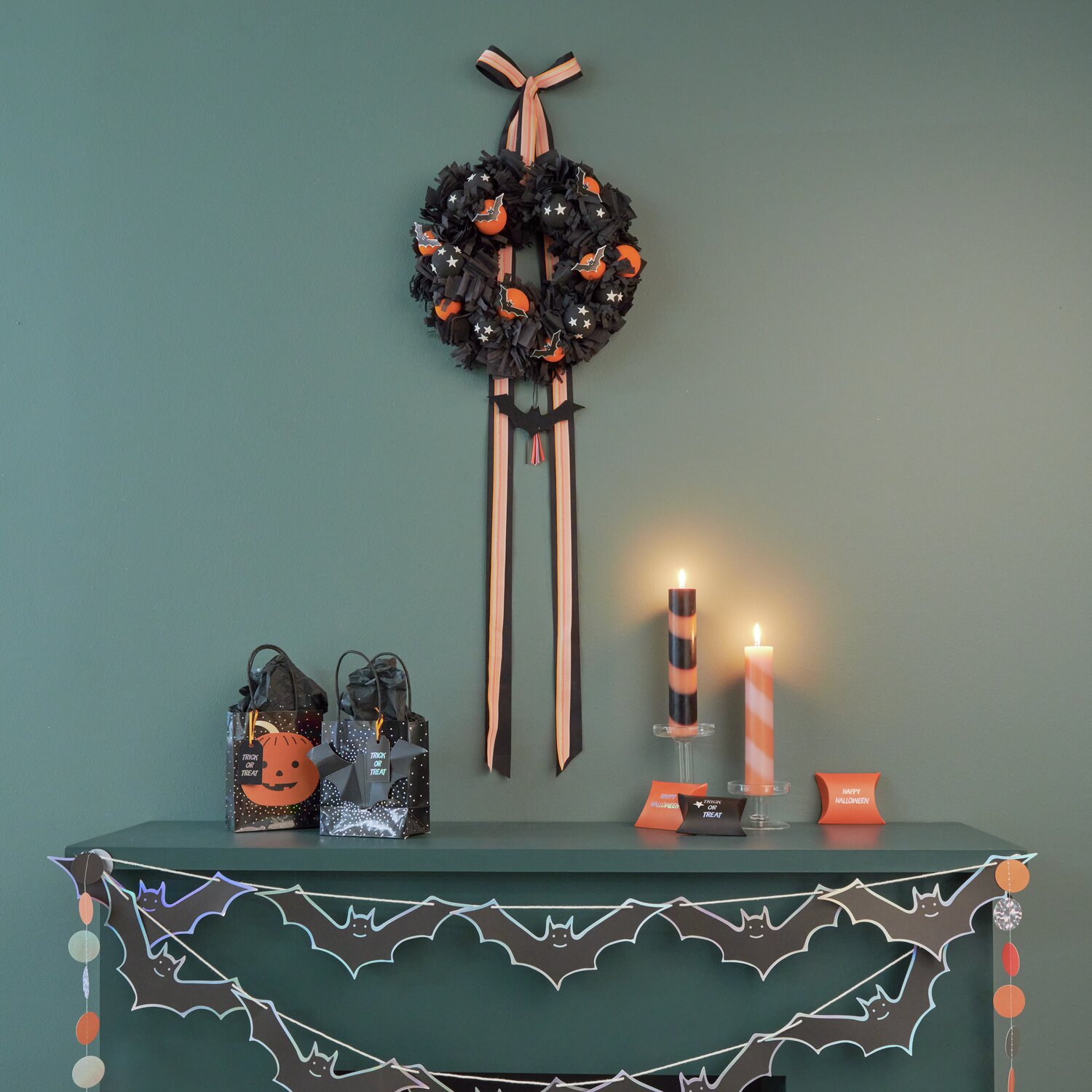 Paper Poetry Girlande Halloween Fledermaus 3m: Dekorative Tischszene mit Kerzen, Girlande und Geschenktüten in Schwarz und Orange für Halloween.