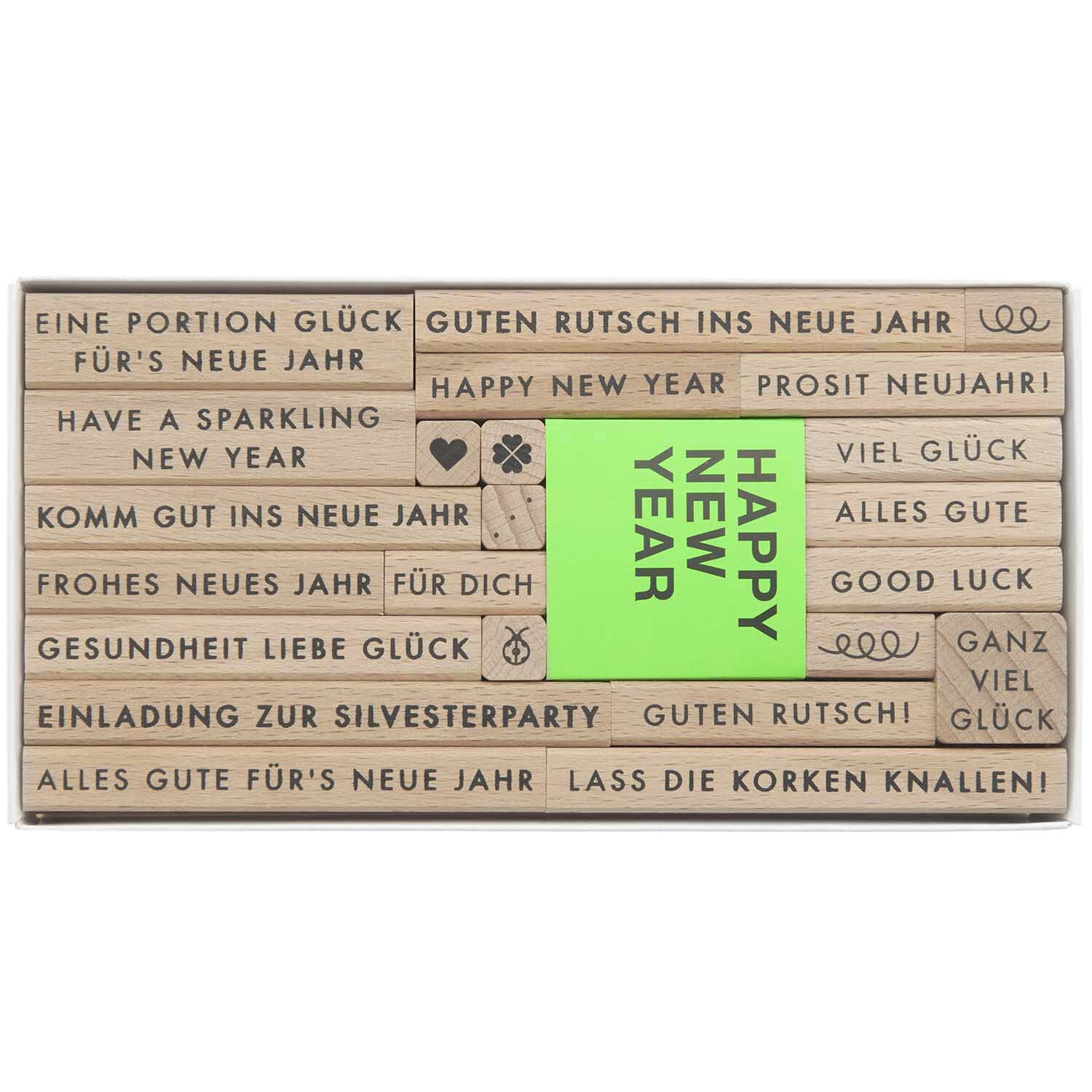 Paper Poetry Stempelset Happy New Year: 24-teiliges Set mit Neujahrsgrüßen und Symbolen auf Holzstempeln. Ideal für kreative Projekte.