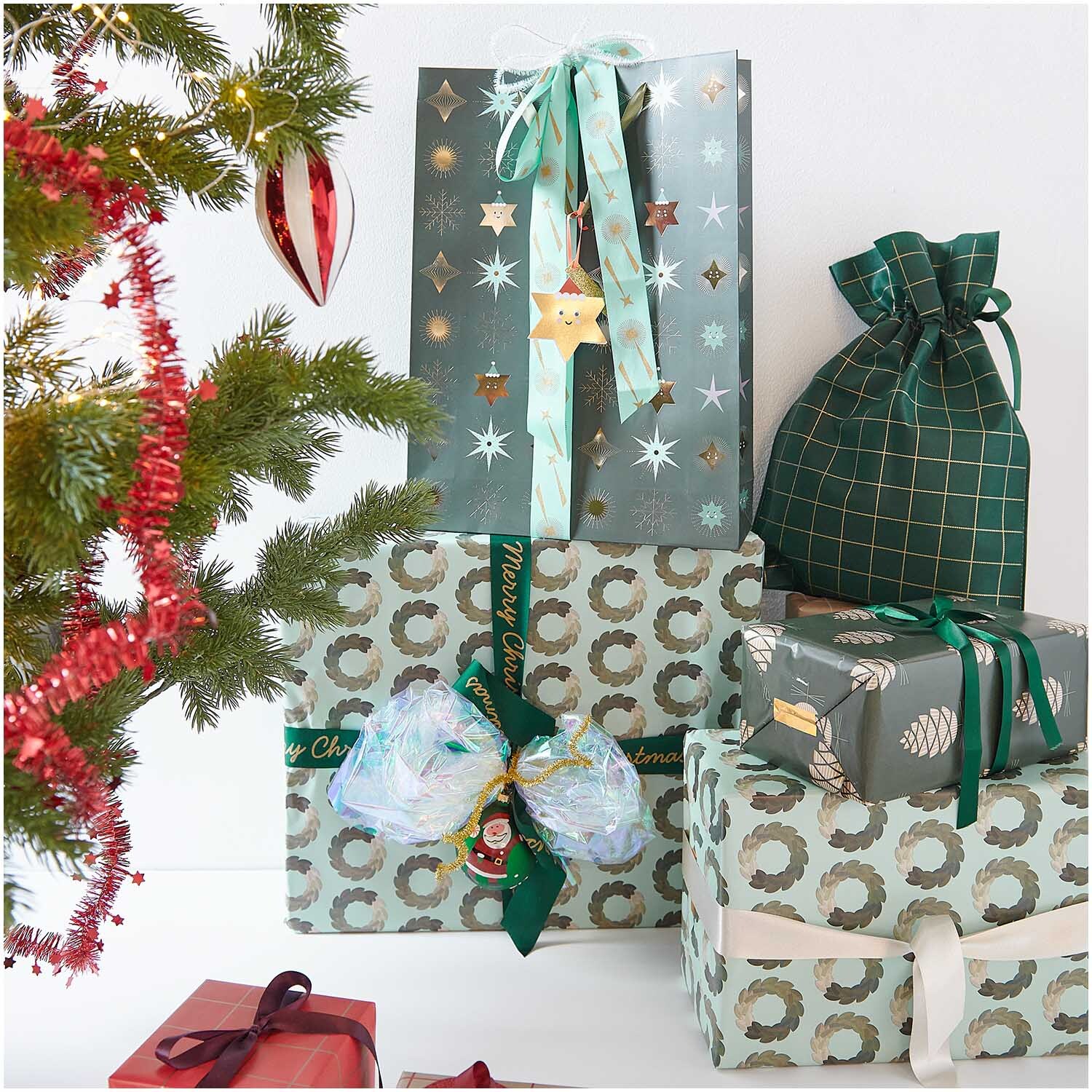 Paper Poetry Geschenkpapier Tannenzapfen umhüllt Geschenke unter einem festlich geschmückten Baum. Ideal für stilvolle Weihnachtsverpackungen.