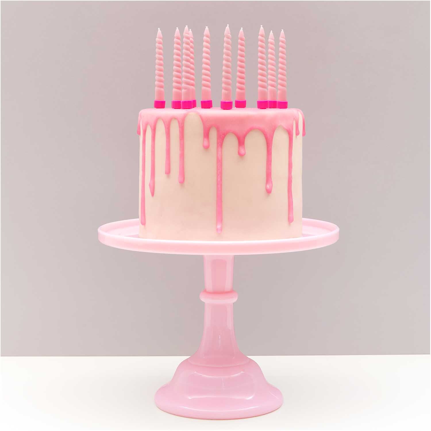 Spiralkerzen 1,2x10cm 10 Stück Farbe Rosa von Rico Design Spiralkerzen 1,2x10cm 10 Stück auf rosa Torte mit Tropfglasur, präsentiert auf rosa Tortenständer.