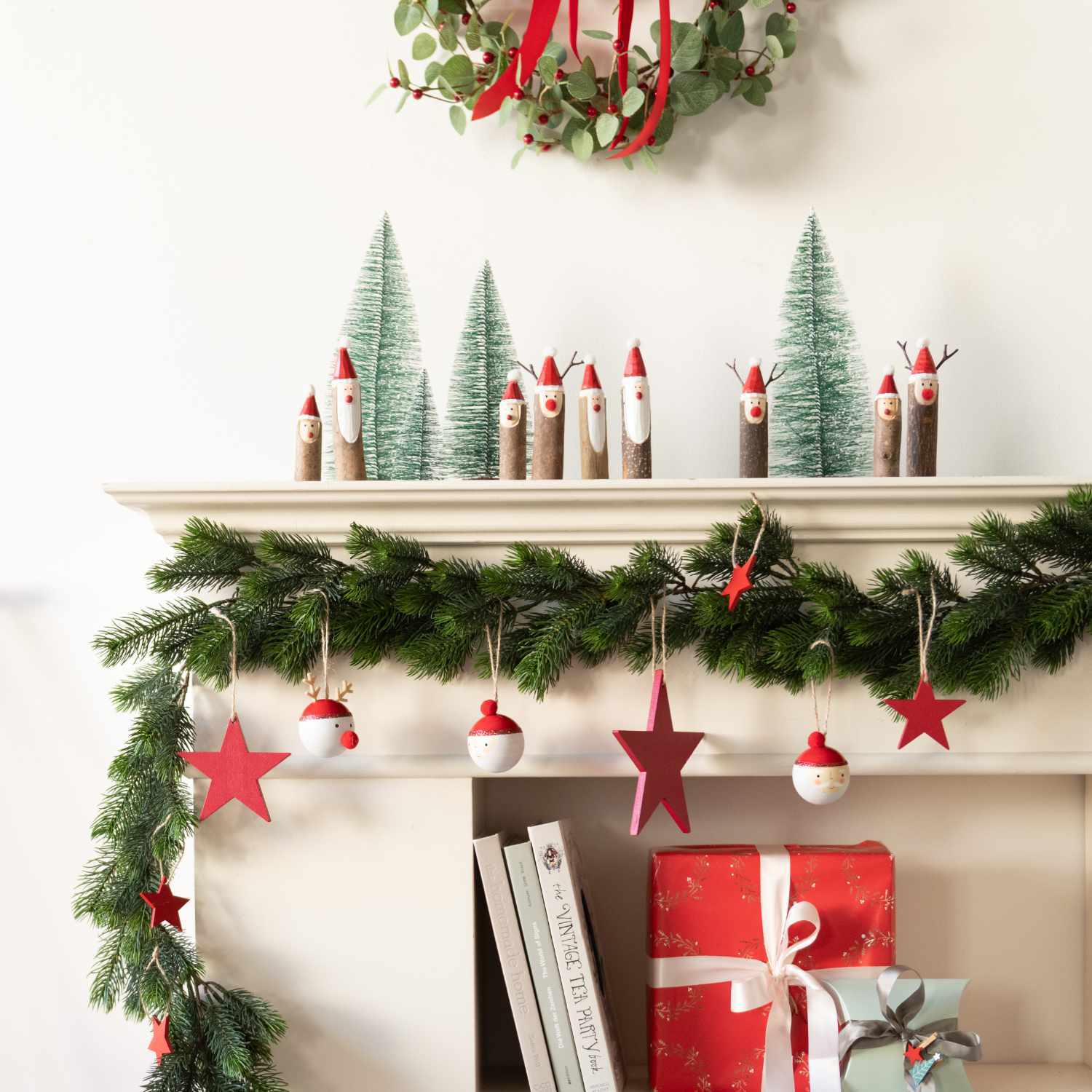 Miniaturtanne grün: Festliche Dekoration mit kleinen Tannen und Weihnachtssternen von Rico Design auf einem Kaminsims.